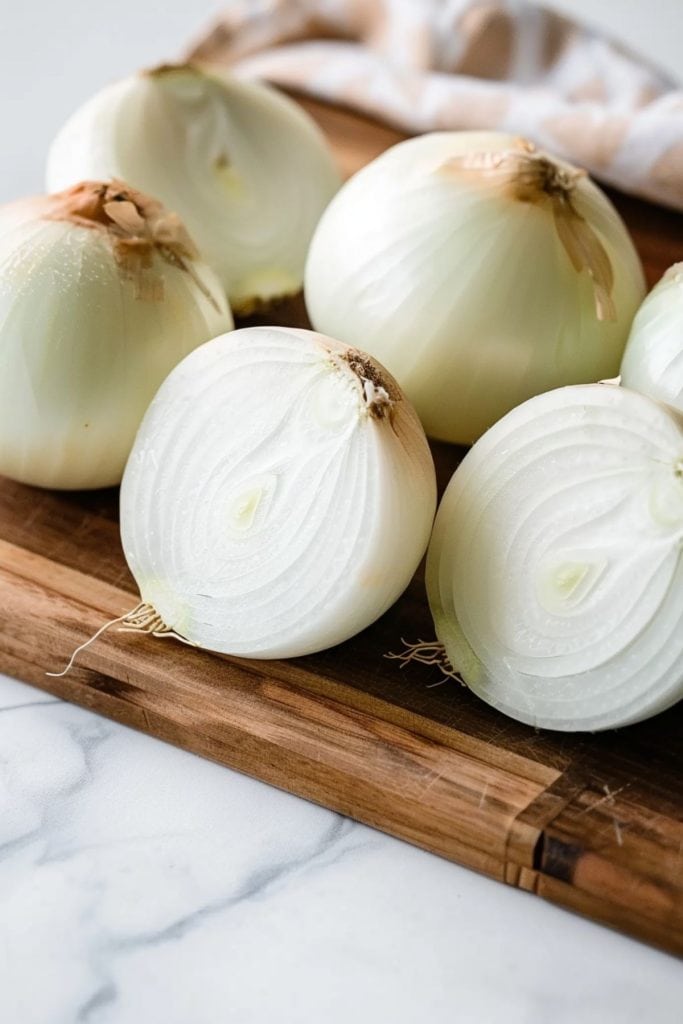 Vidalia onions on a chopping board, cut in half and whole