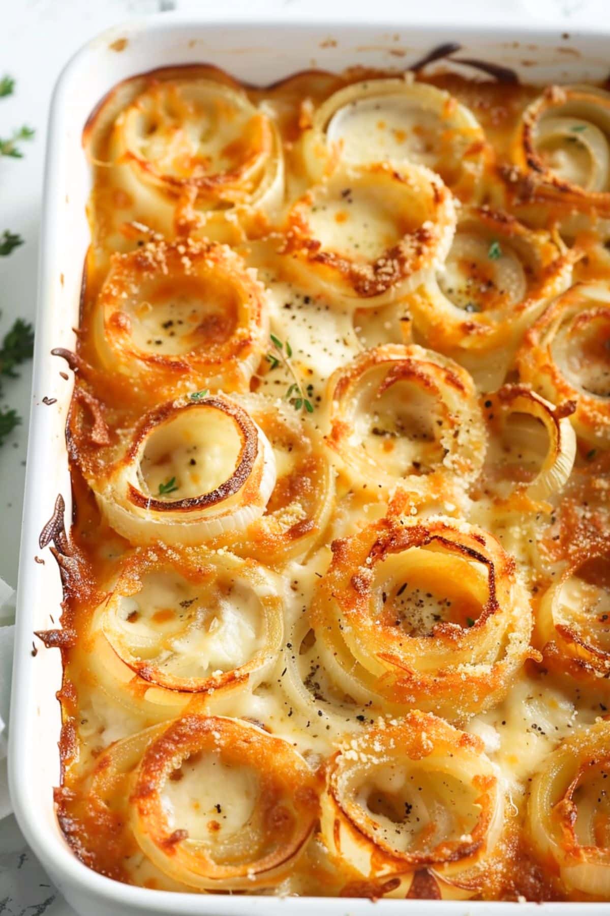 Tennessee onions baked in a rectangular white baking dish, topped with crispy Parmesan cheese