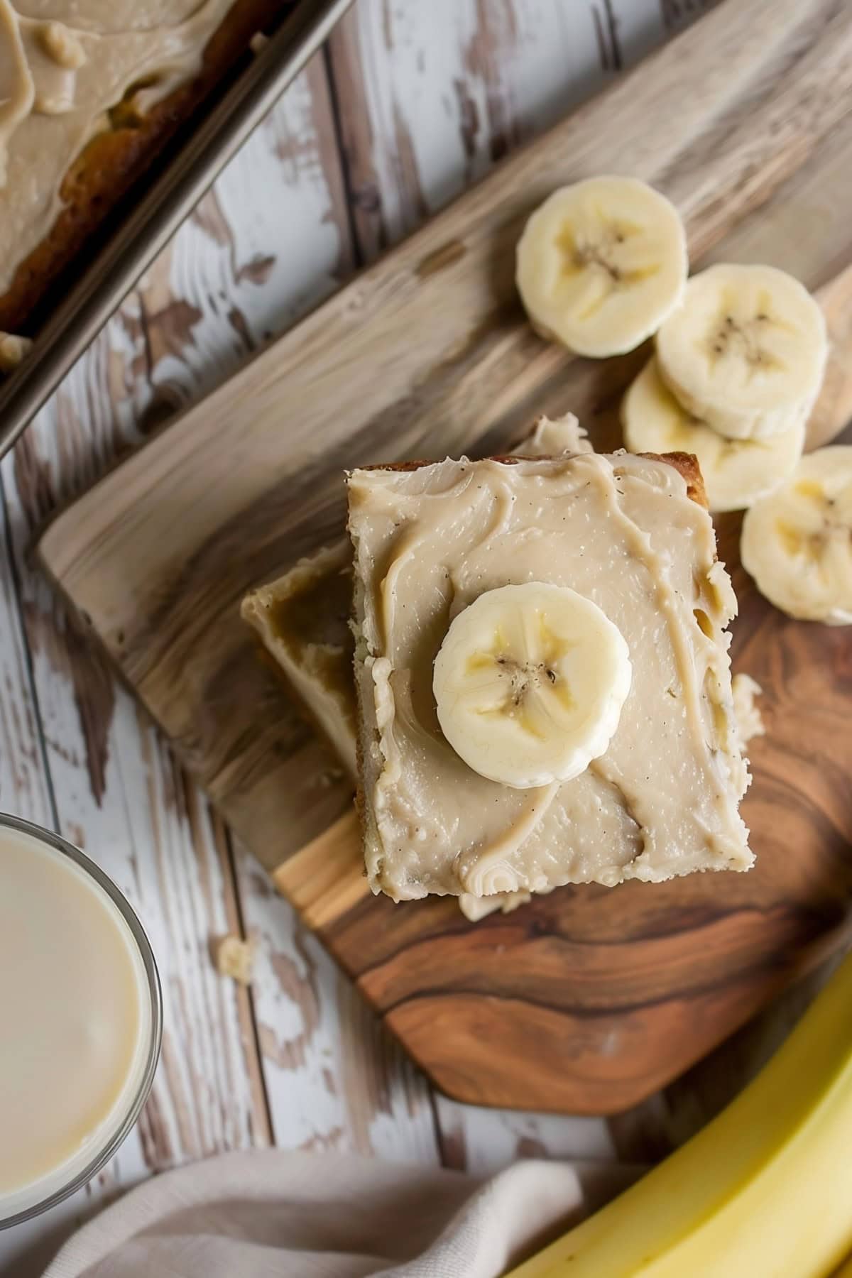 A square slice of Banana Bread with Brown Butter Frosting garnished with a slice of banana on top.