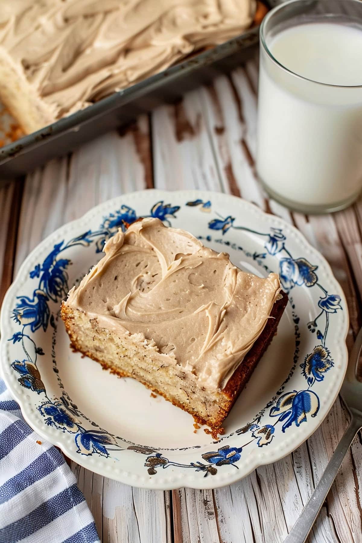 A slice of Banana Bread with Brown Butter Frosting served on a white blue vintage design plate served on a wooden table. 