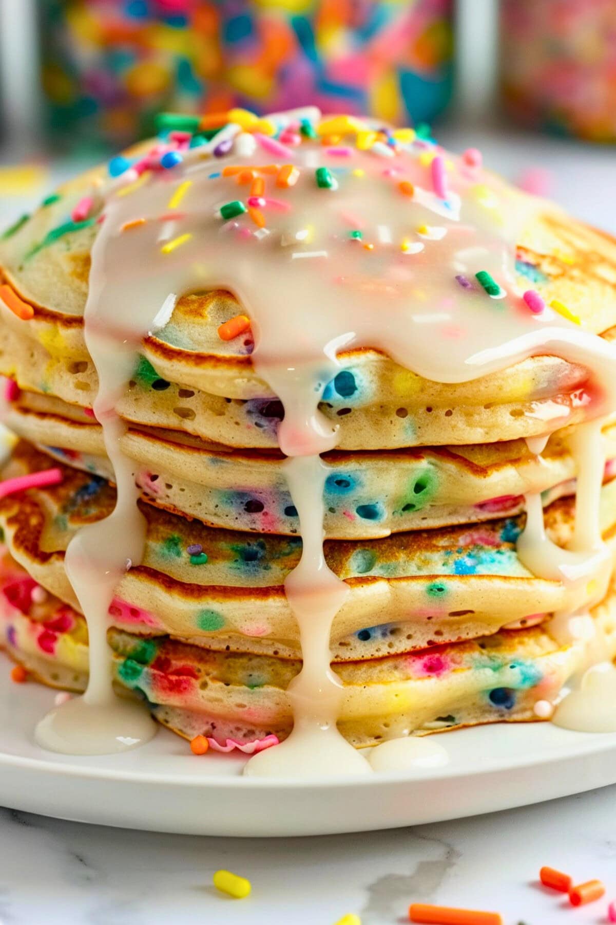 Stack of funfetti pancakes drizzled with vanilla sugar glaze and candy sprinkles.