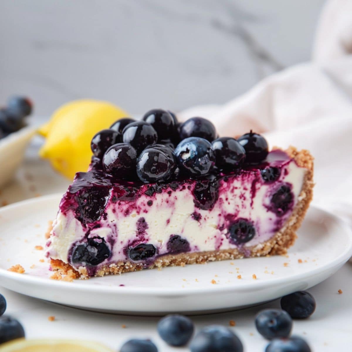 A slice of blueberry lemon cheesecake served on a white plate.