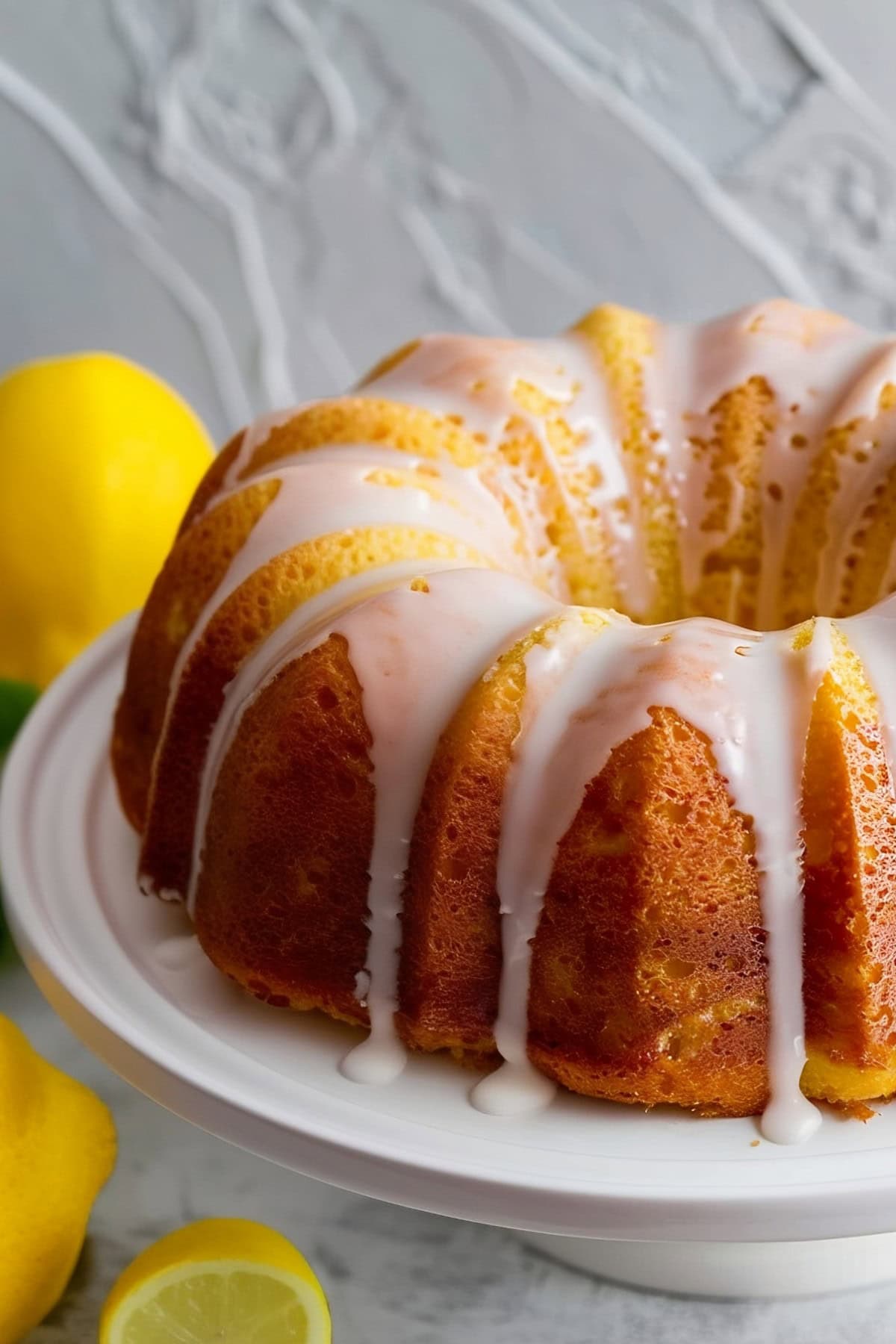 Lemon bundt cake with glaze in a cake stand.