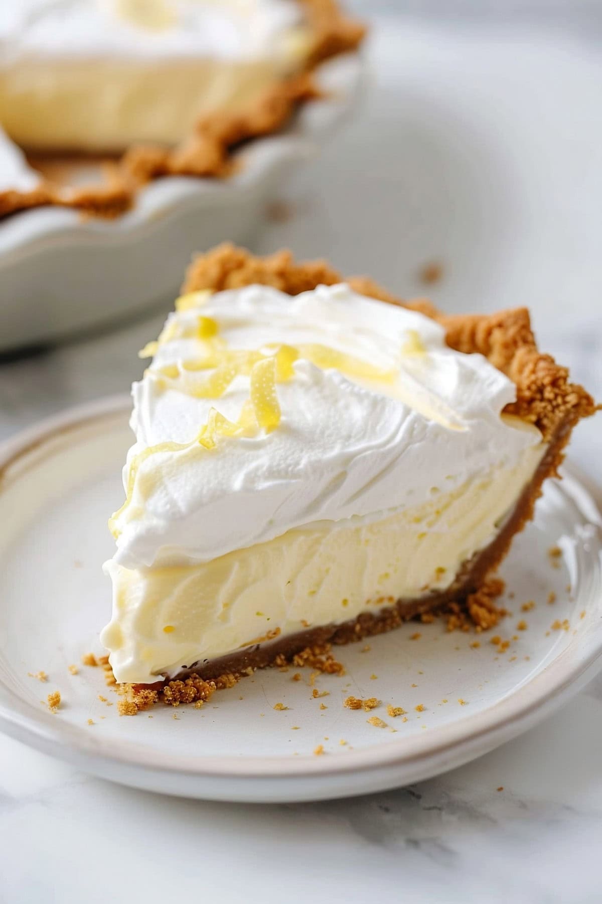 A slice of Lemon Cream Pie in a white plate.