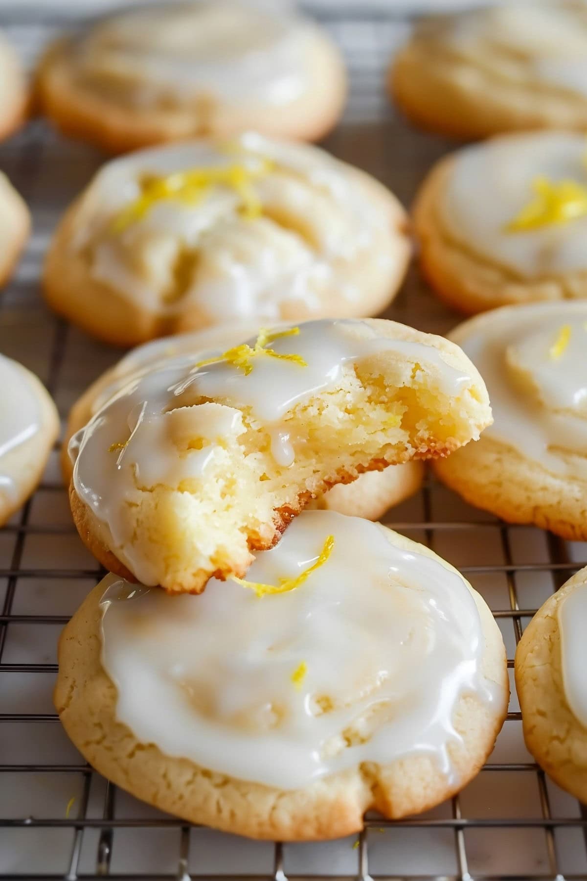 Lemon meltaway cookies in a cooling rack. One piece is bitten to show its texture.