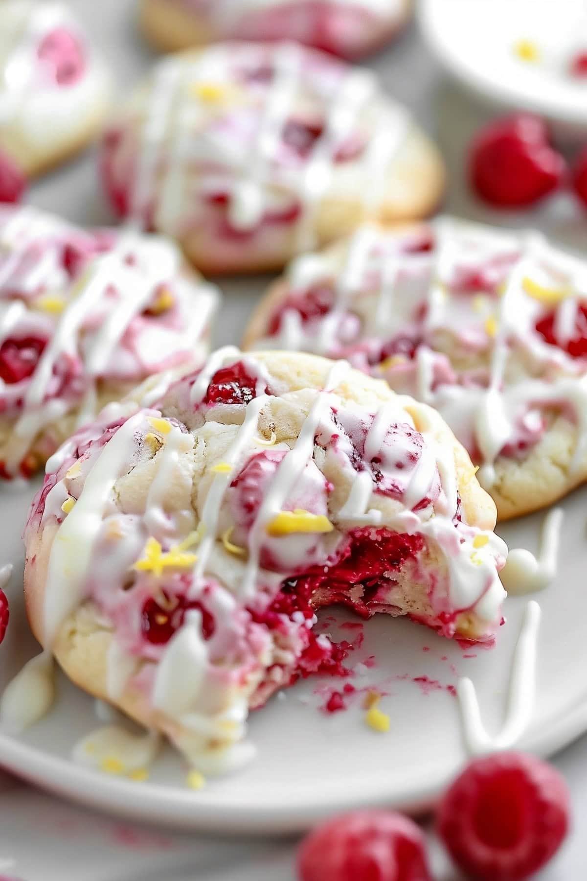 Lemon raspberry cookies with glaze on a plate with a bite taken out of one