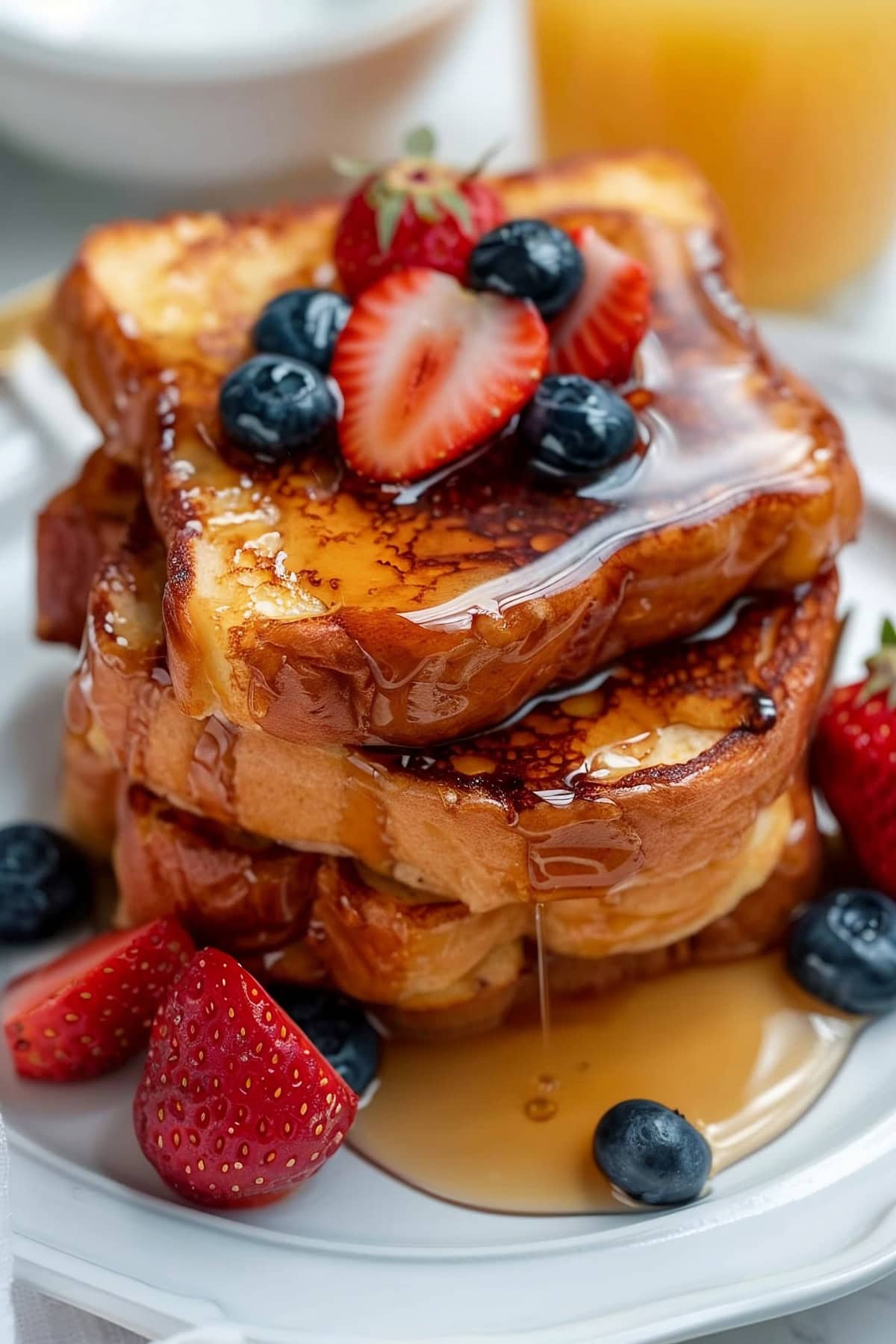 French Toast with Berries in a White Plate Drizzled with Maple Syrup