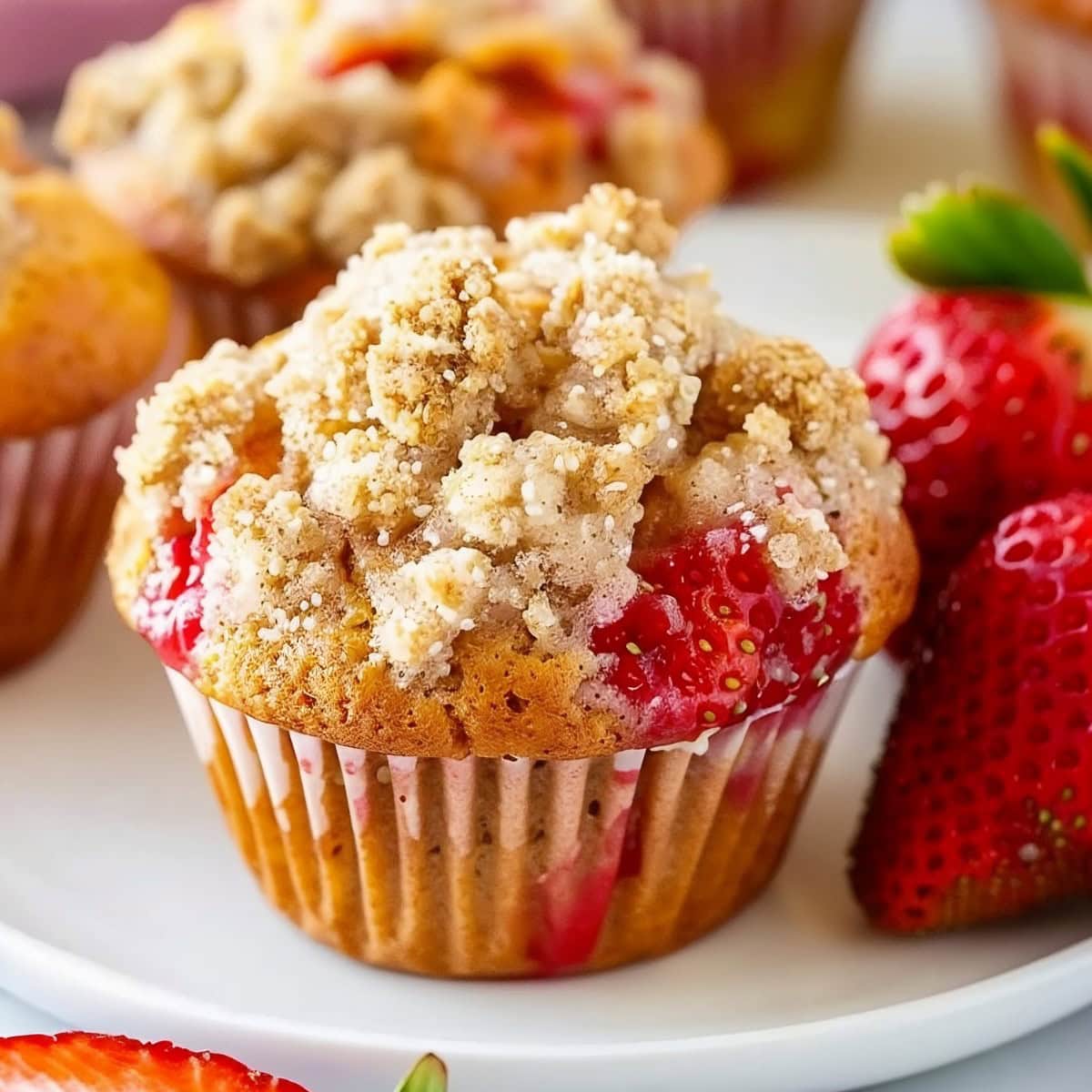 Strawberry Cream Cheese Muffins in a white plate garnished with fresh strawberries.