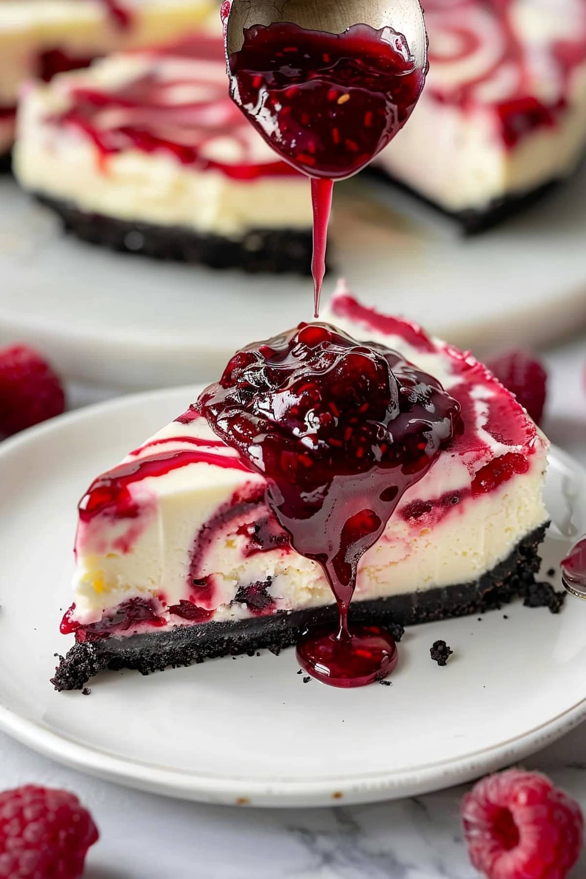 Raspberry jam dripping on top of a slice of raspberry cheesecake served on a plate.