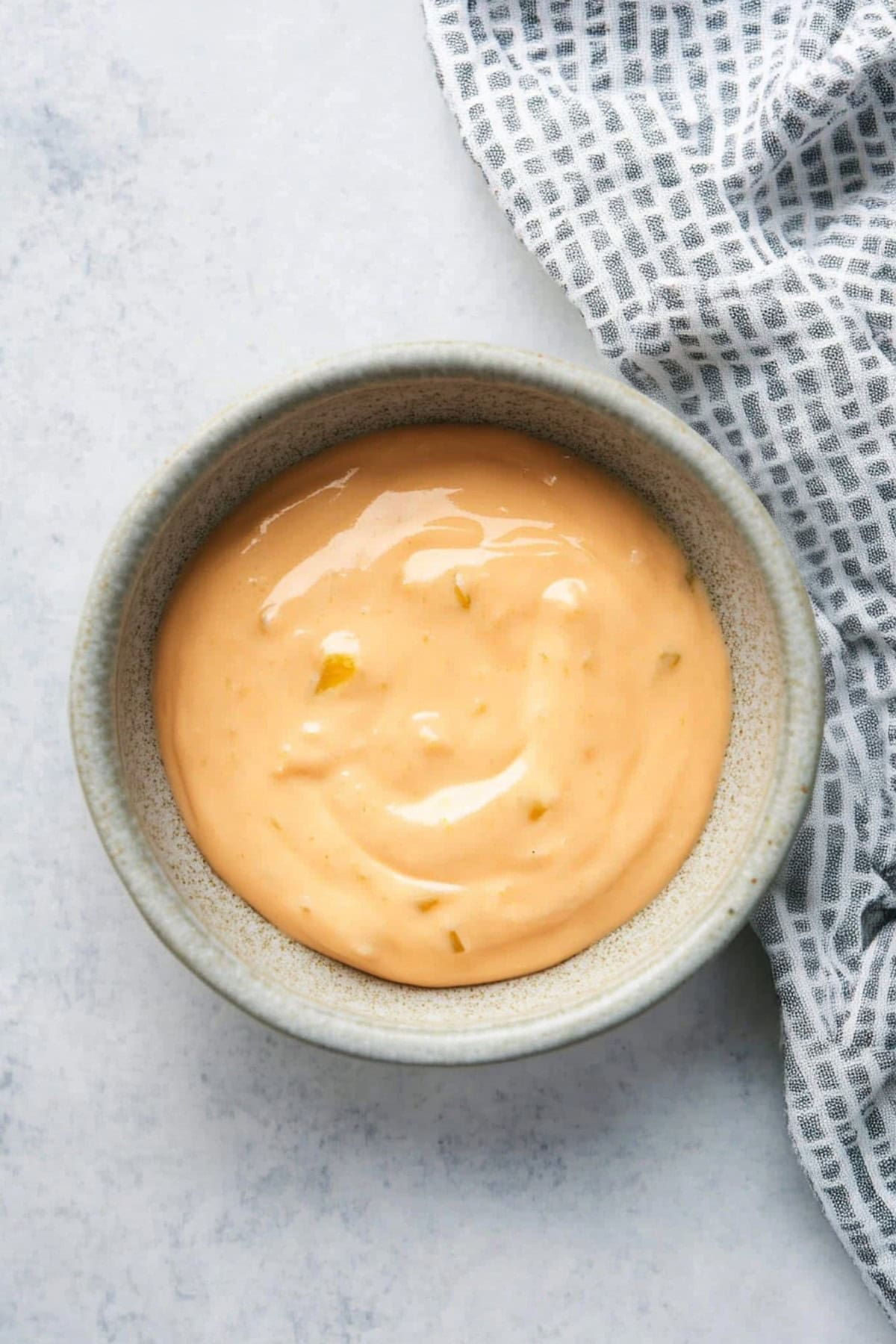 Spicy mayo in a bowl on a white marble table, top view