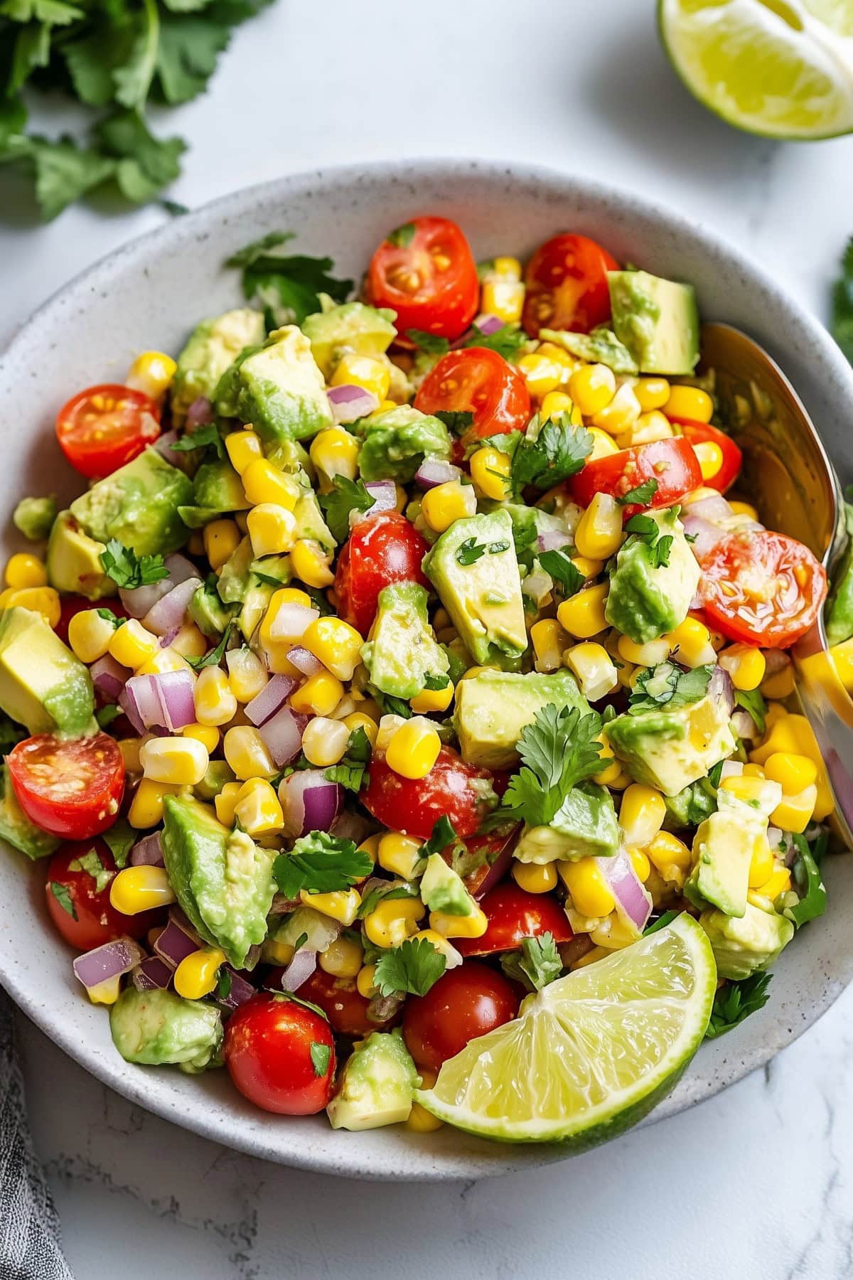 Close-up of creamy avocado chunks mixed with fresh corn kernels in a salad.