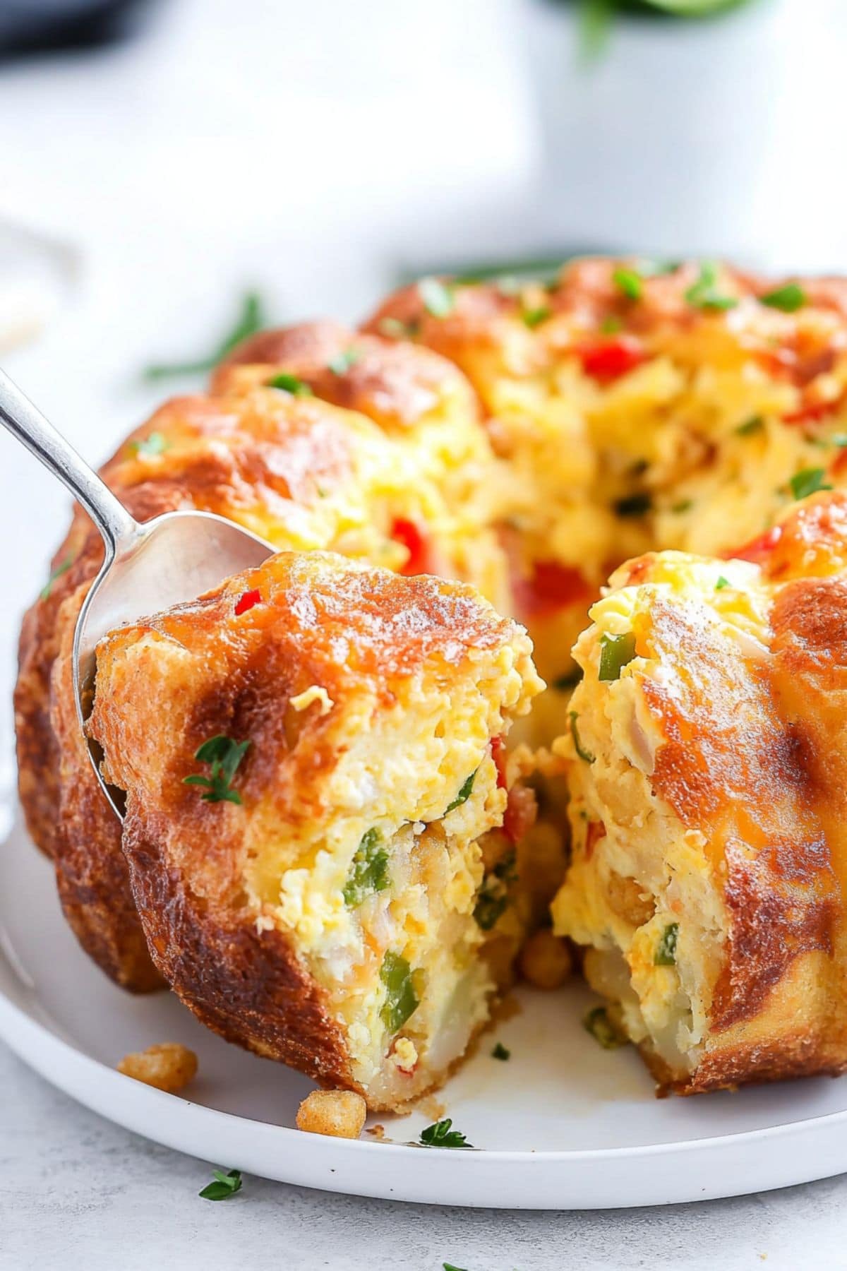 Sliced breakfast bundt cake with fluffy eggs, melty cheese, and crispy tater tots, studded with veggies and ham.