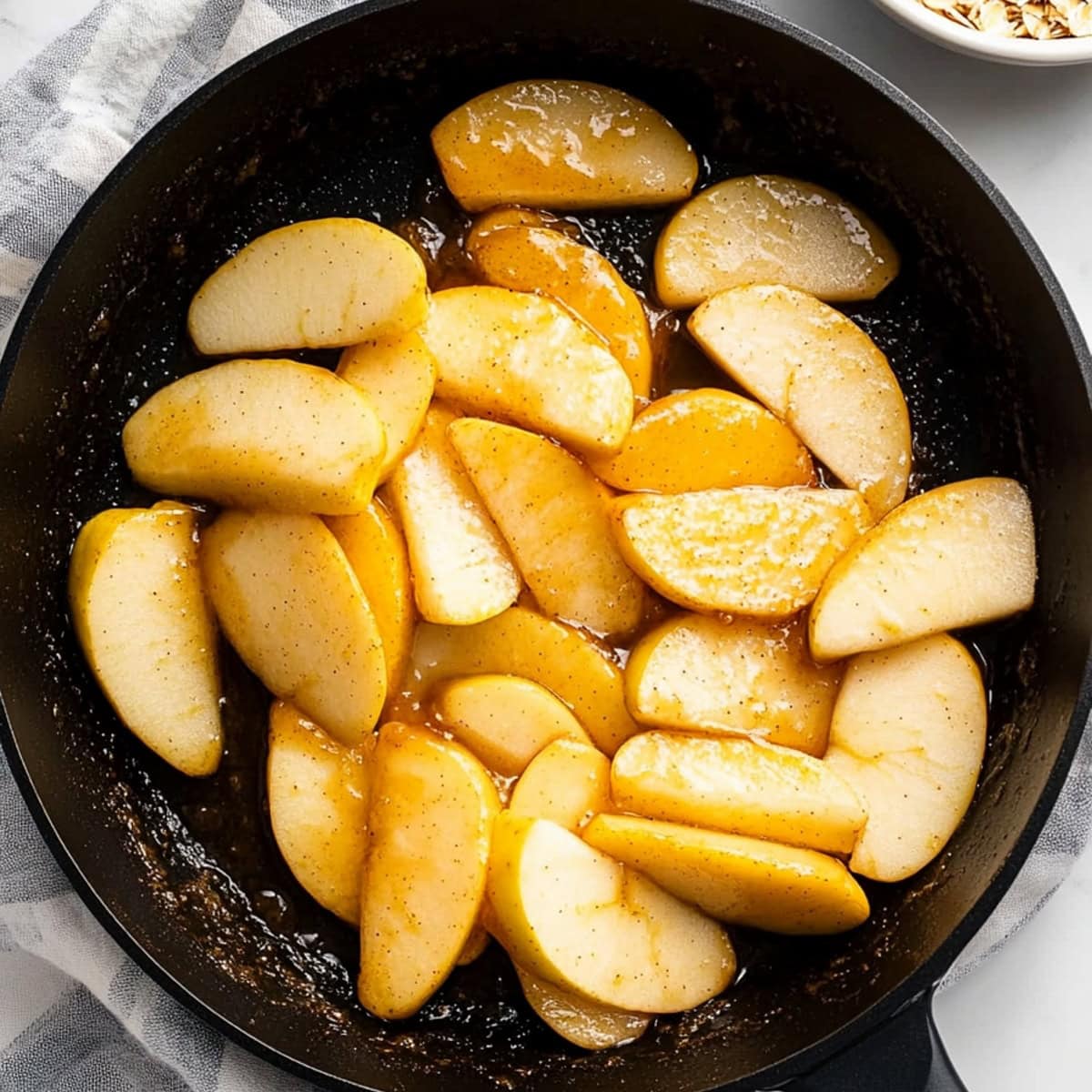 A skillet filled with sliced caramelized apples, top view