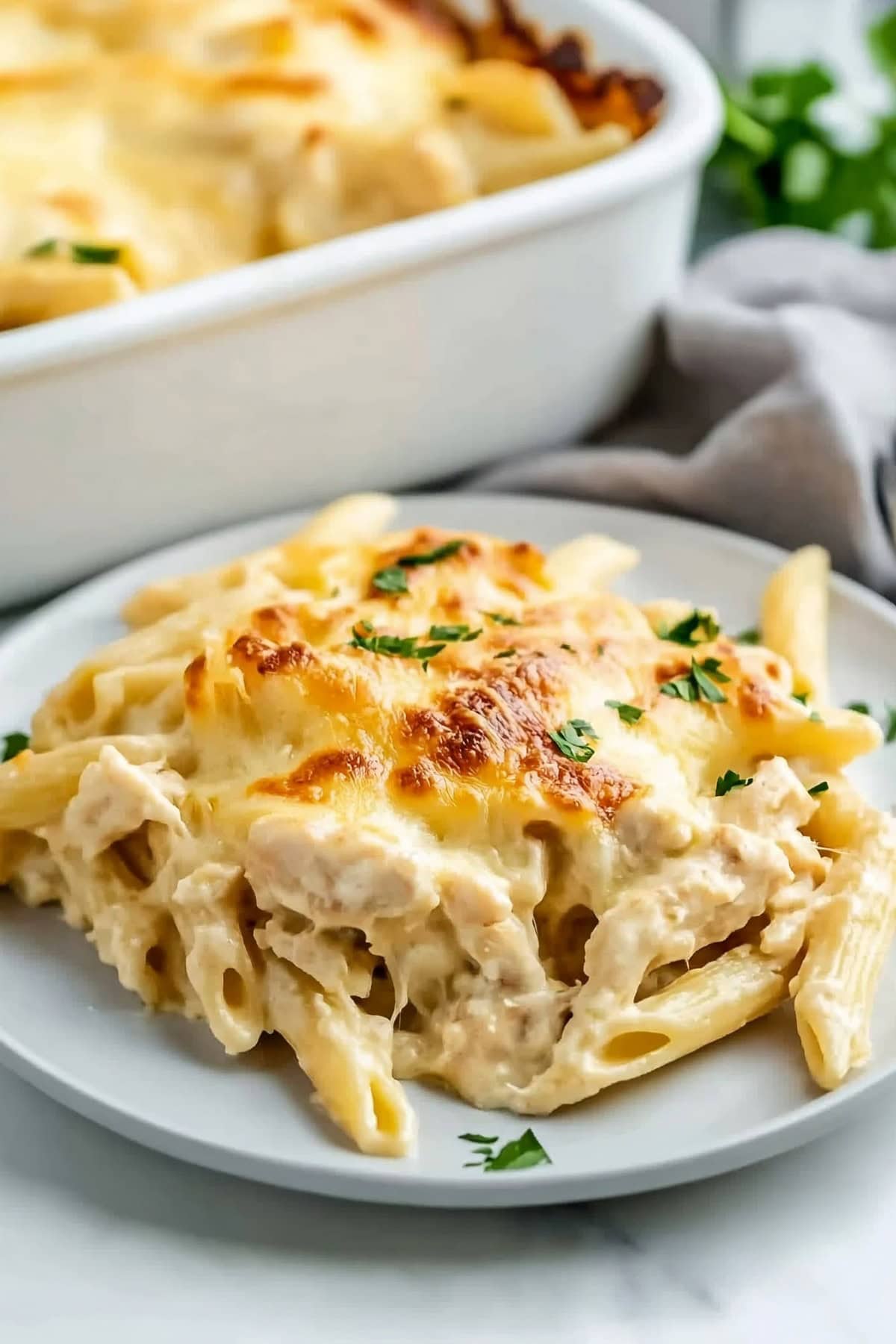 Chicken Alfredo with a creamy sauce and garnished with herbs.