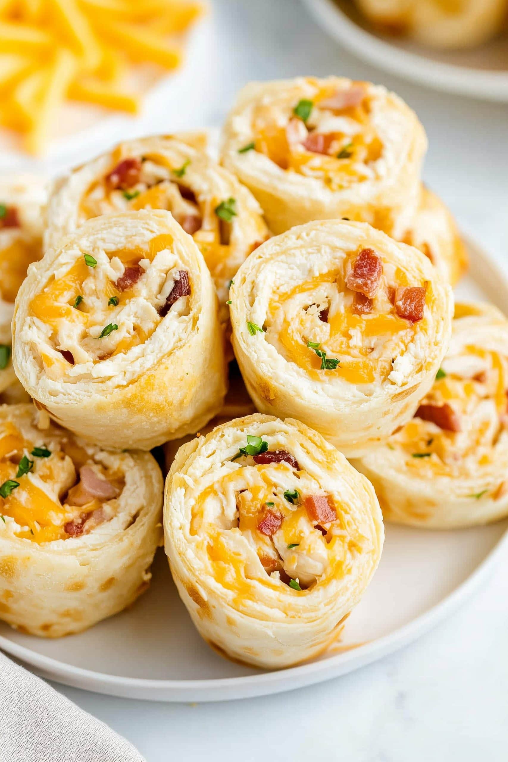 Chicken bacon ranch pinwheels with chopped chives in a plate.