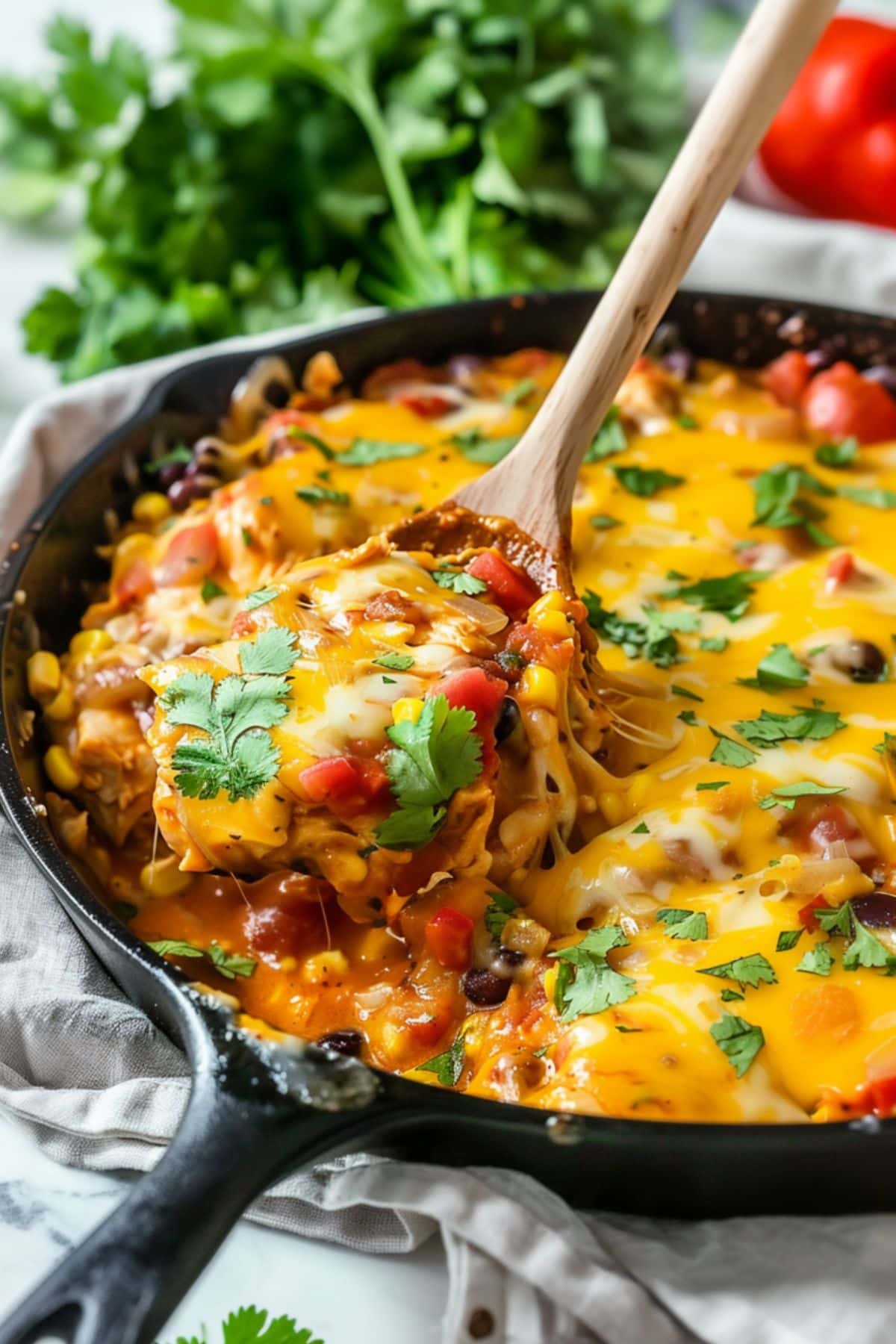 Wooden ladle scooping a serving of cheesy chicken enchiladas. 