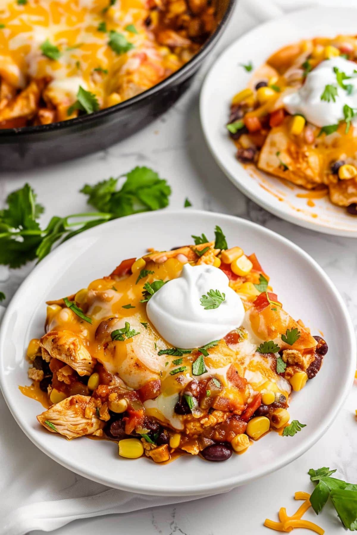 Two servings of chicken enchiladas in a plate garnished with sour cream.