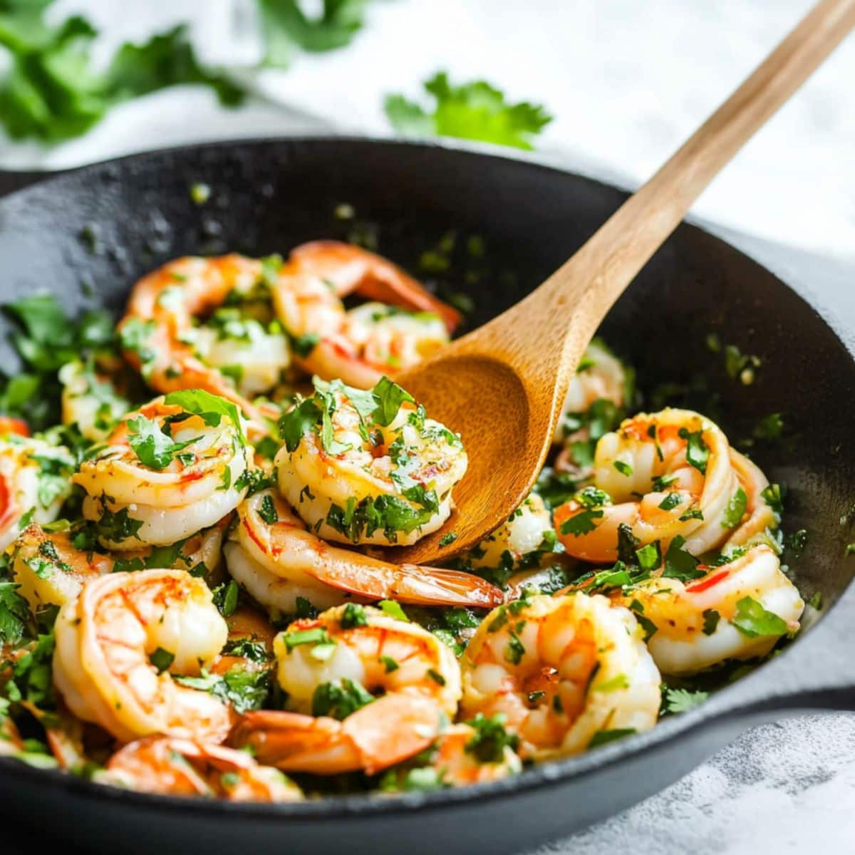 Shrimp tossed in lime juice and cilantro in a cast iron skillet pan.