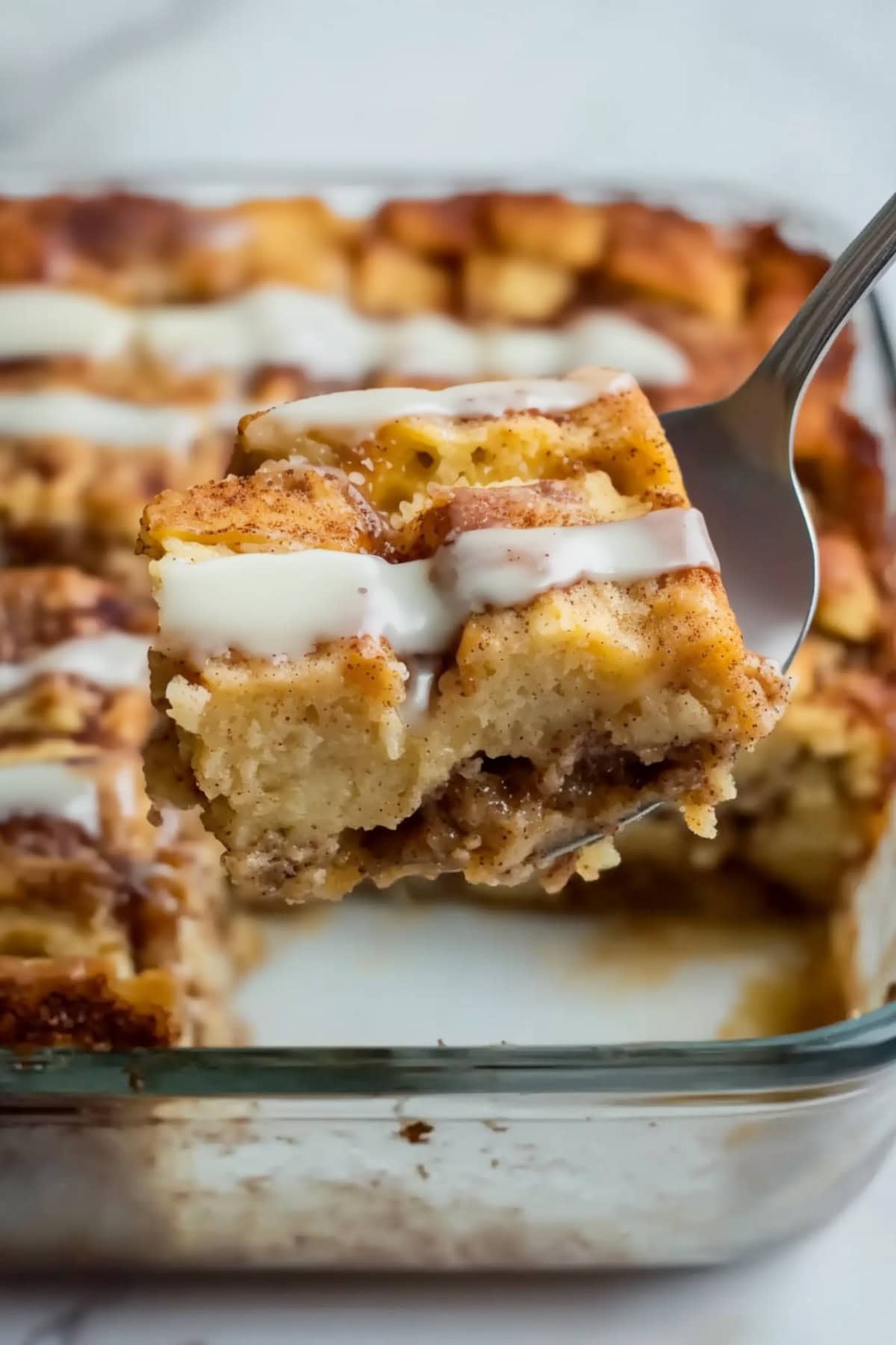 Spoon scooping a slice of cinnamon roll casserole.