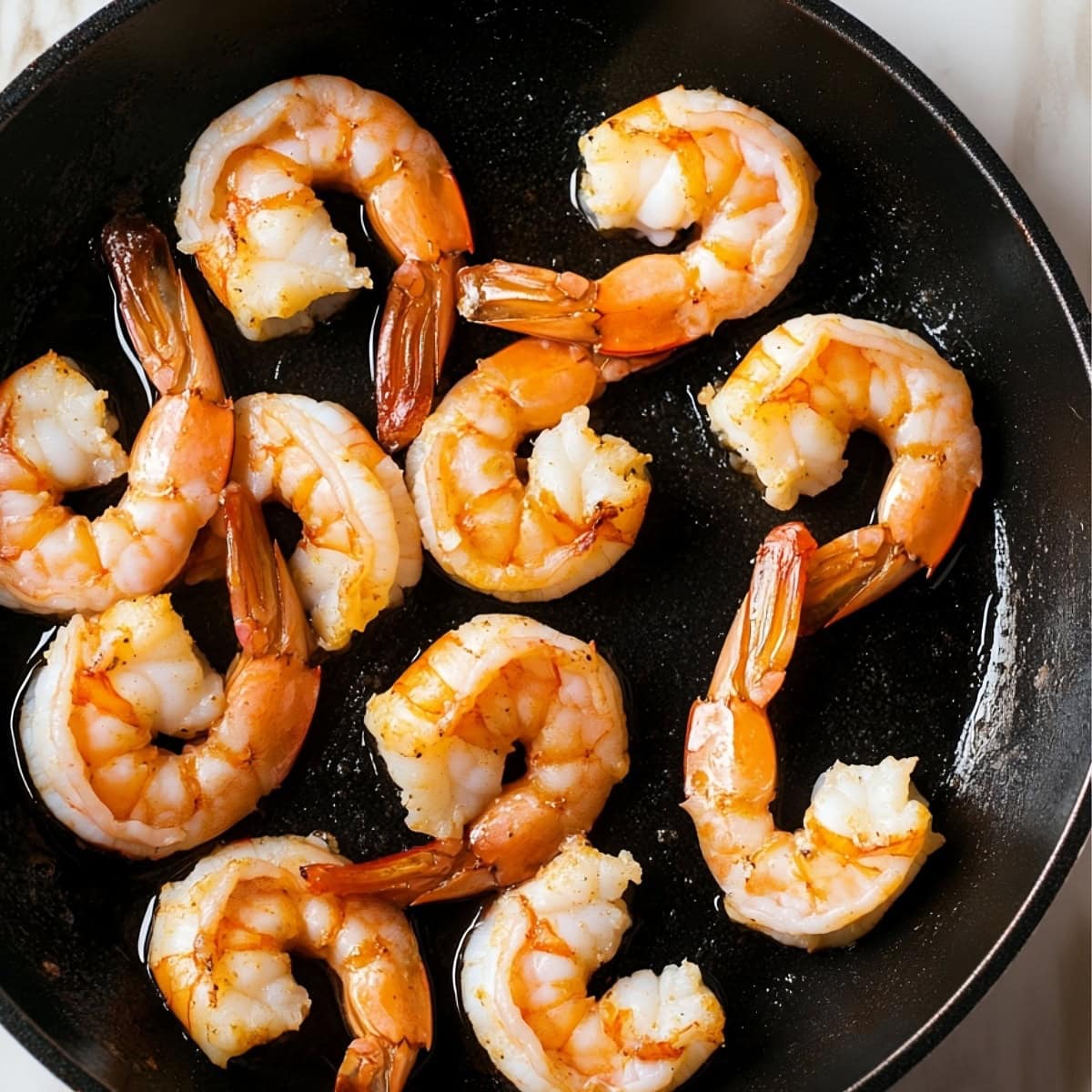 Large shrimps cooked in a skillet, top view.