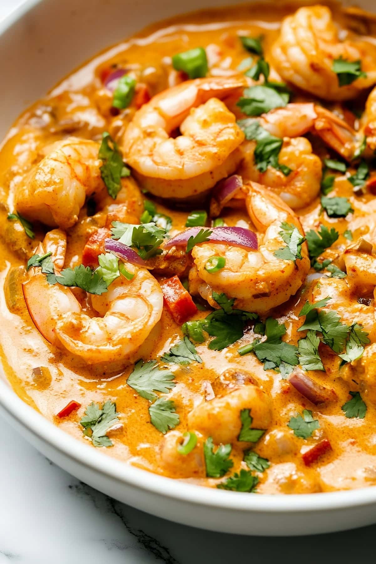 A bowl of creamy chipotle shrimp coated in a smoky, spicy cream sauce, garnished with fresh cilantro.