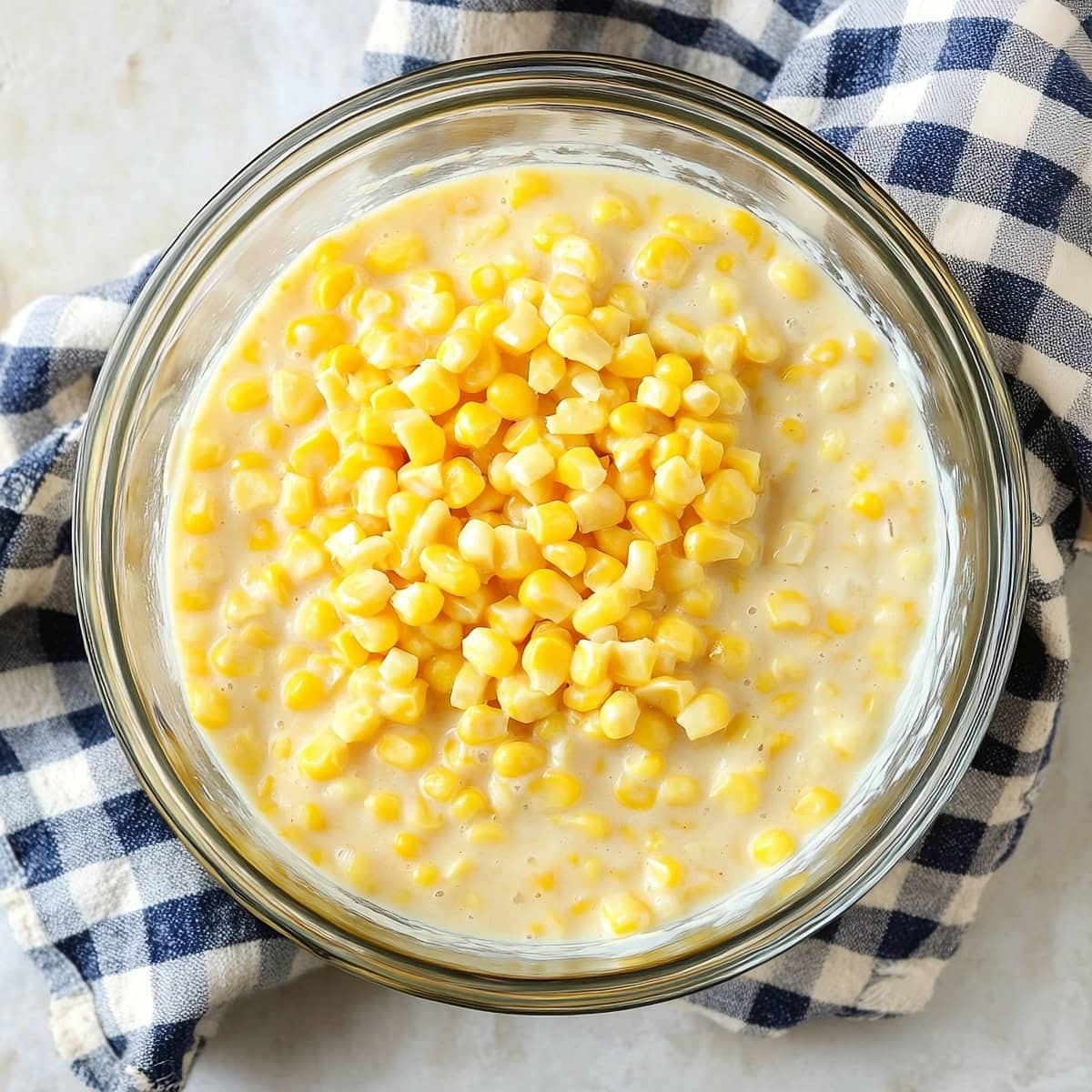 A glass bowl filled with creamed corn, top view.