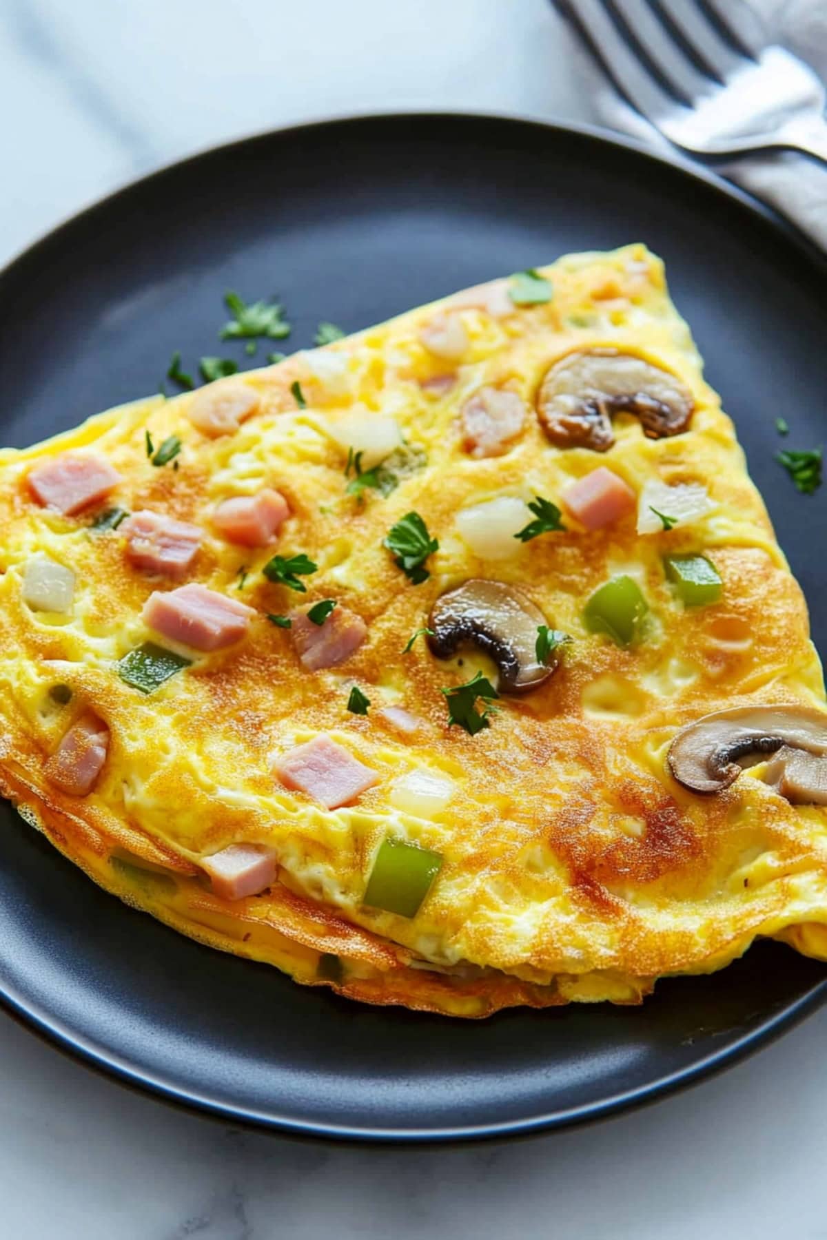 Fluffy Denver omelette filled with diced ham, bell peppers, onions, and melted cheese.