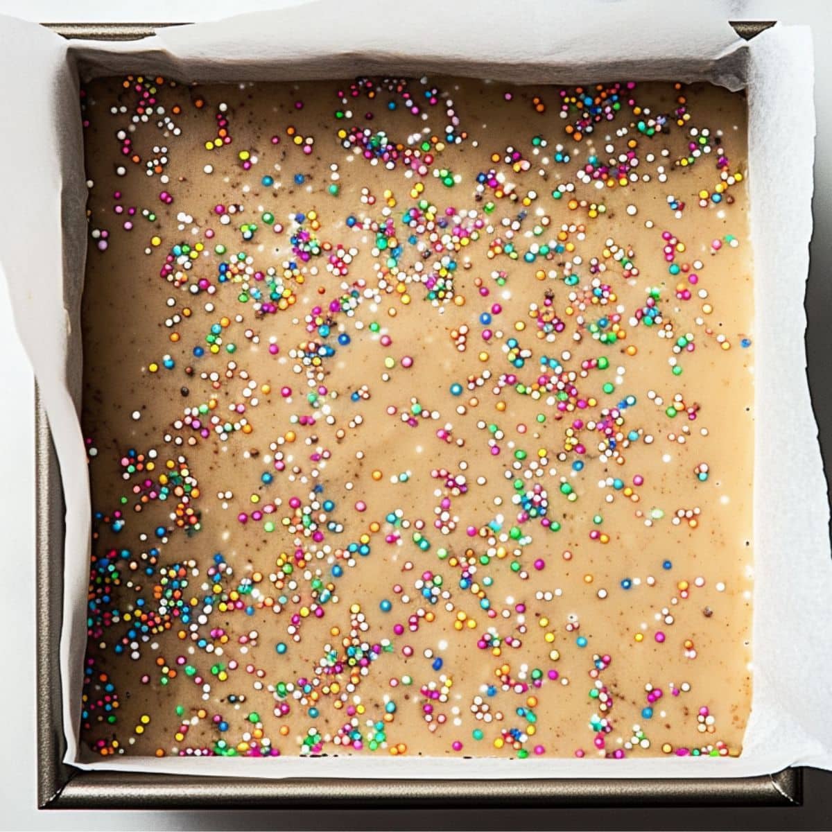 Ginger bread fudge mixture with candy sprinkles in a baking pan, top view