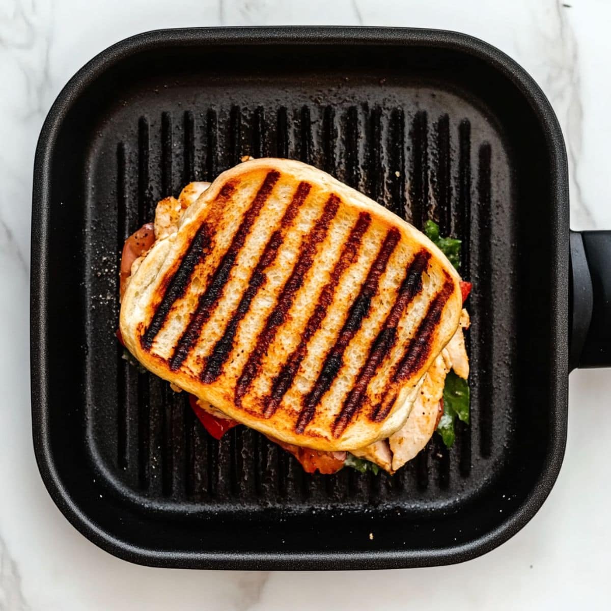 Chicken panini sandwich in a grill pan, top view.