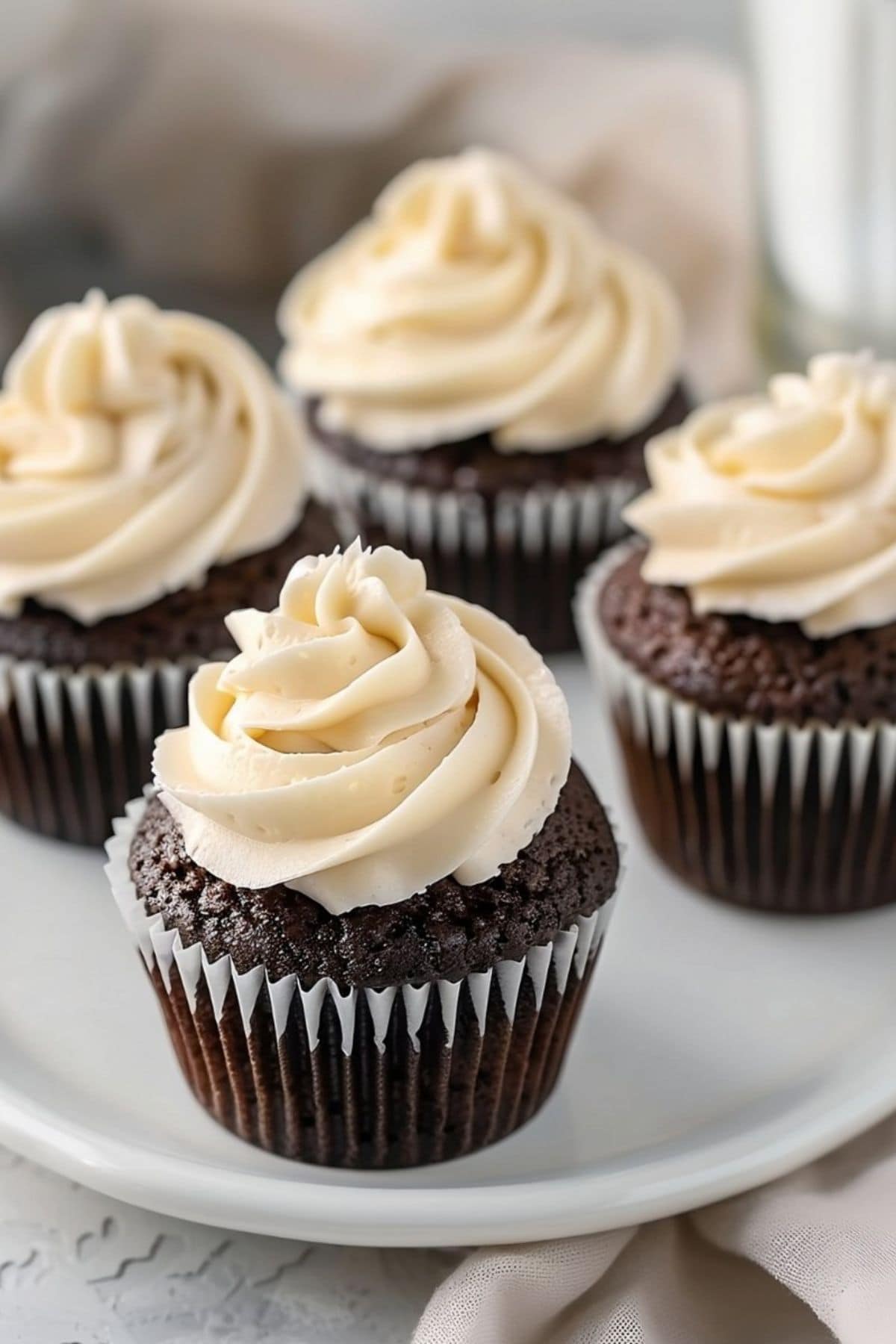 Guinness chocolate cupcakes with Baileys frosting on top served on a white plate.