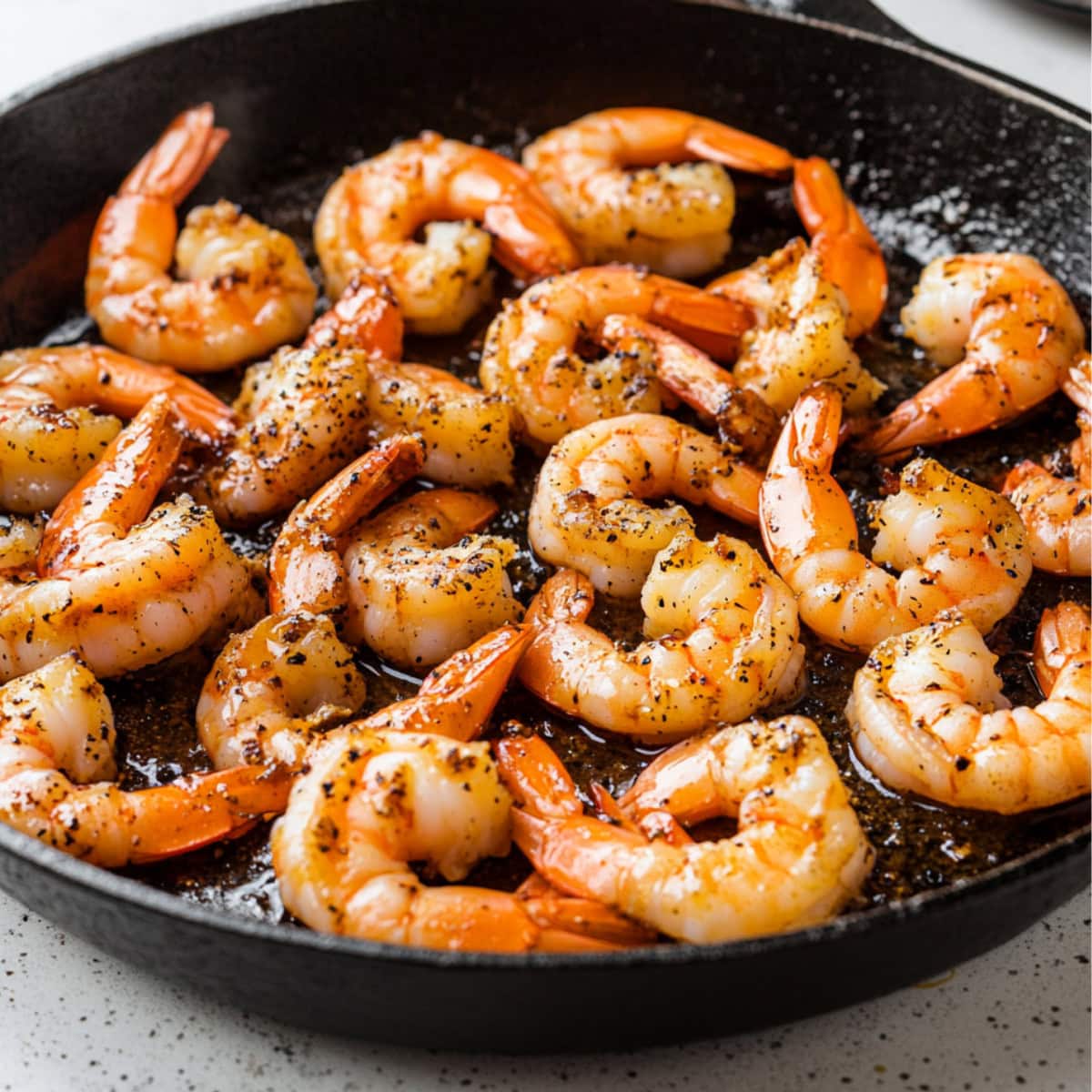 Shrimp tossed in hibachi sauce made with soy sauce, mirin, sesame oil, minced garlic, and black pepper in a cast iron skillet pan.