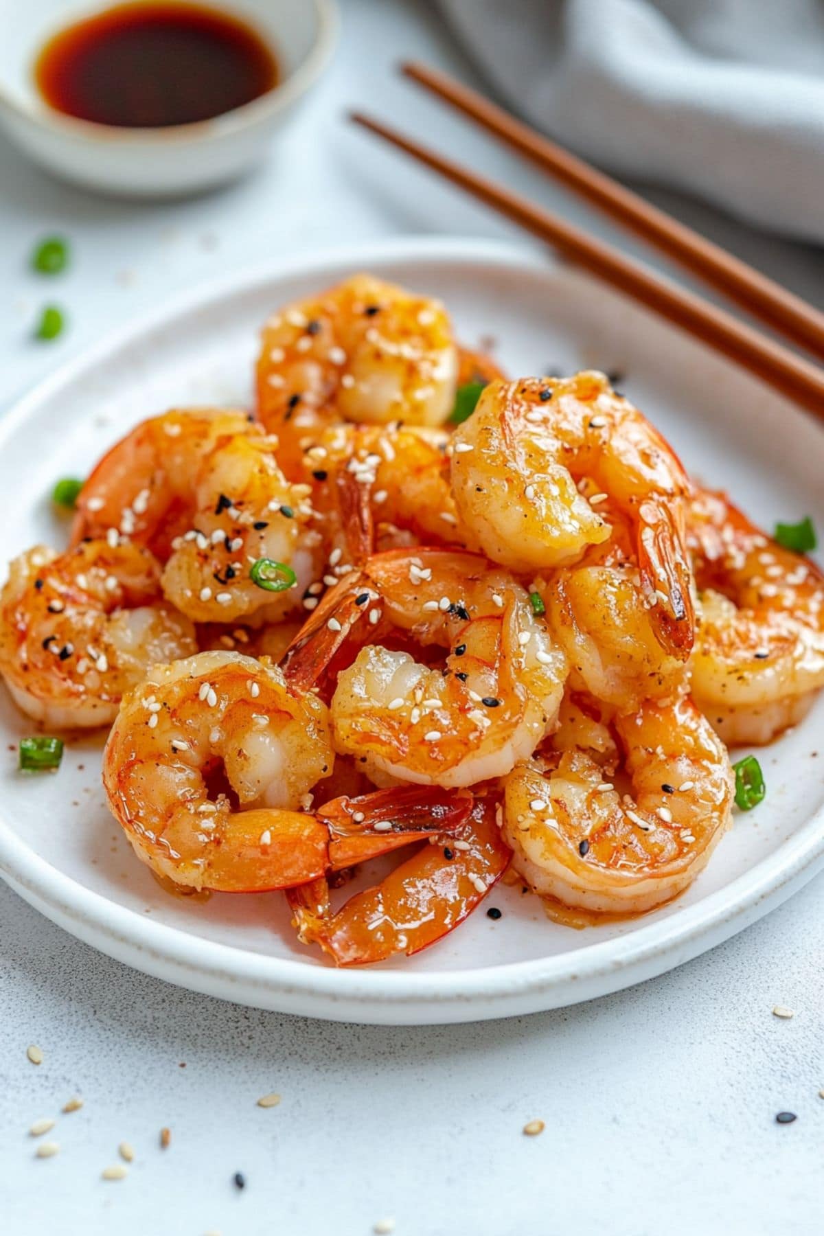 Shrimp tossed in hibachi sauce served on a white plate, pair of chopsticks on the side. 