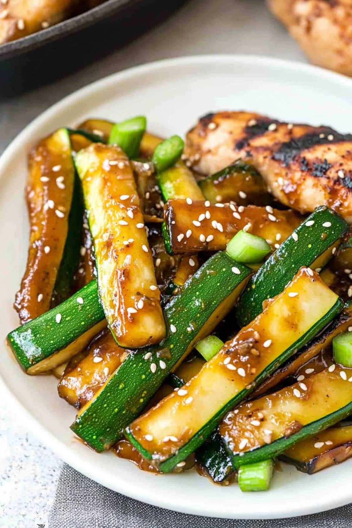 Hibachi zucchini with sauce garnished with sesame seeds served on a white plate.