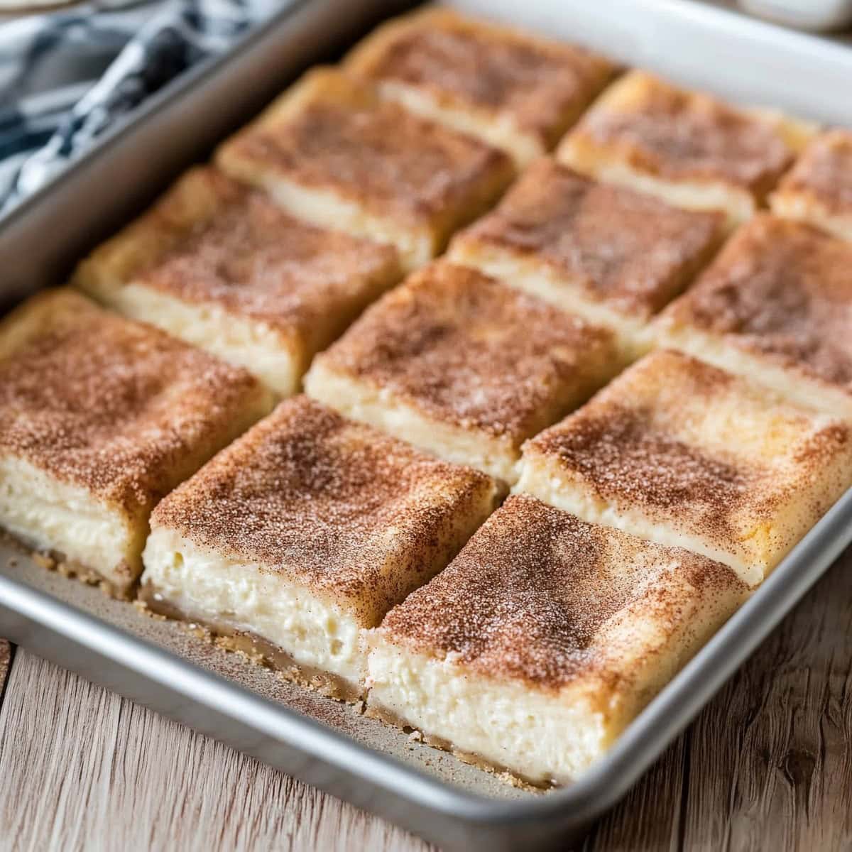 Tray of sliced churro cheesecake bars topped with cinnamon sugar