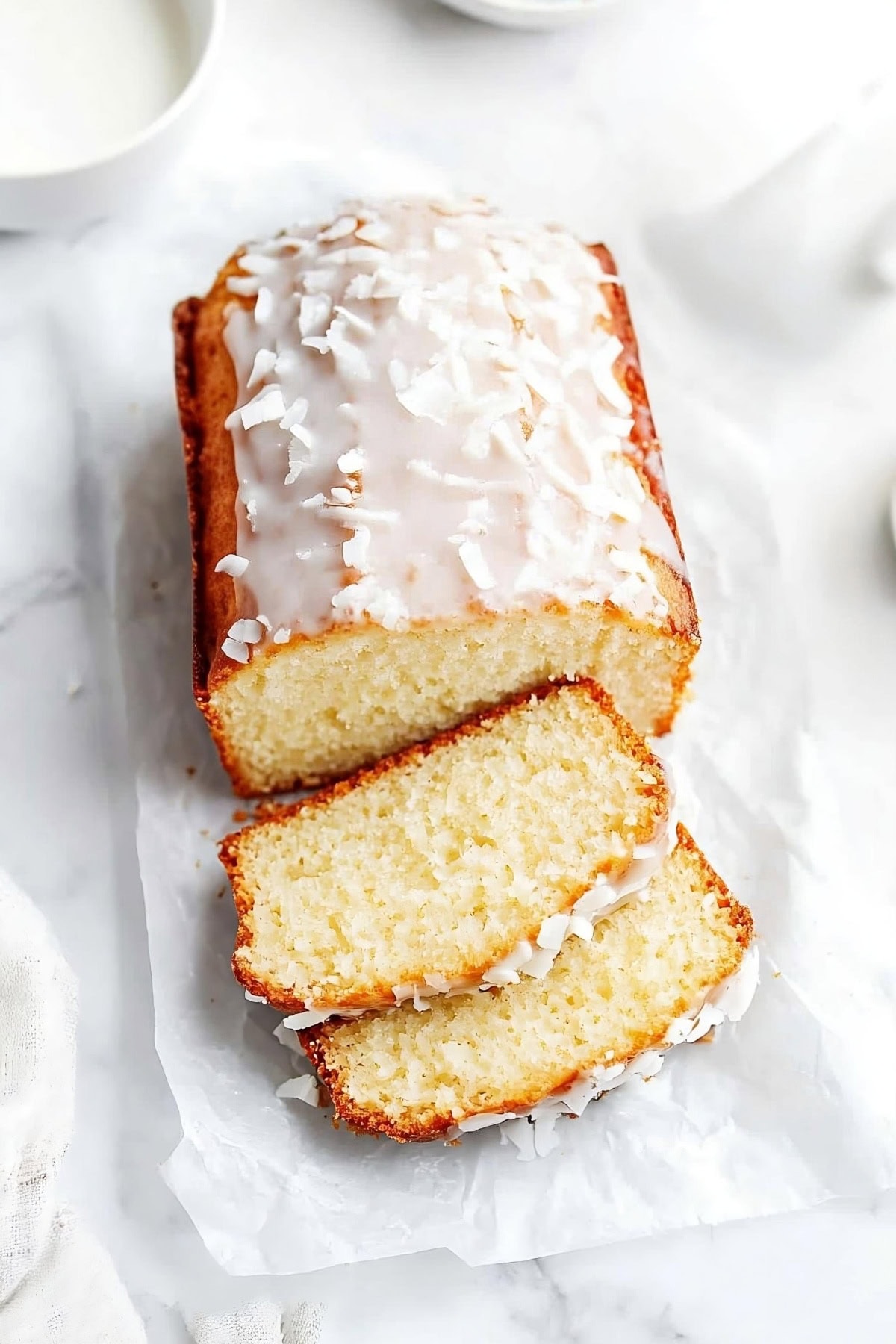 Coconut bread with a rich glaze, garnished with coconut flakes.