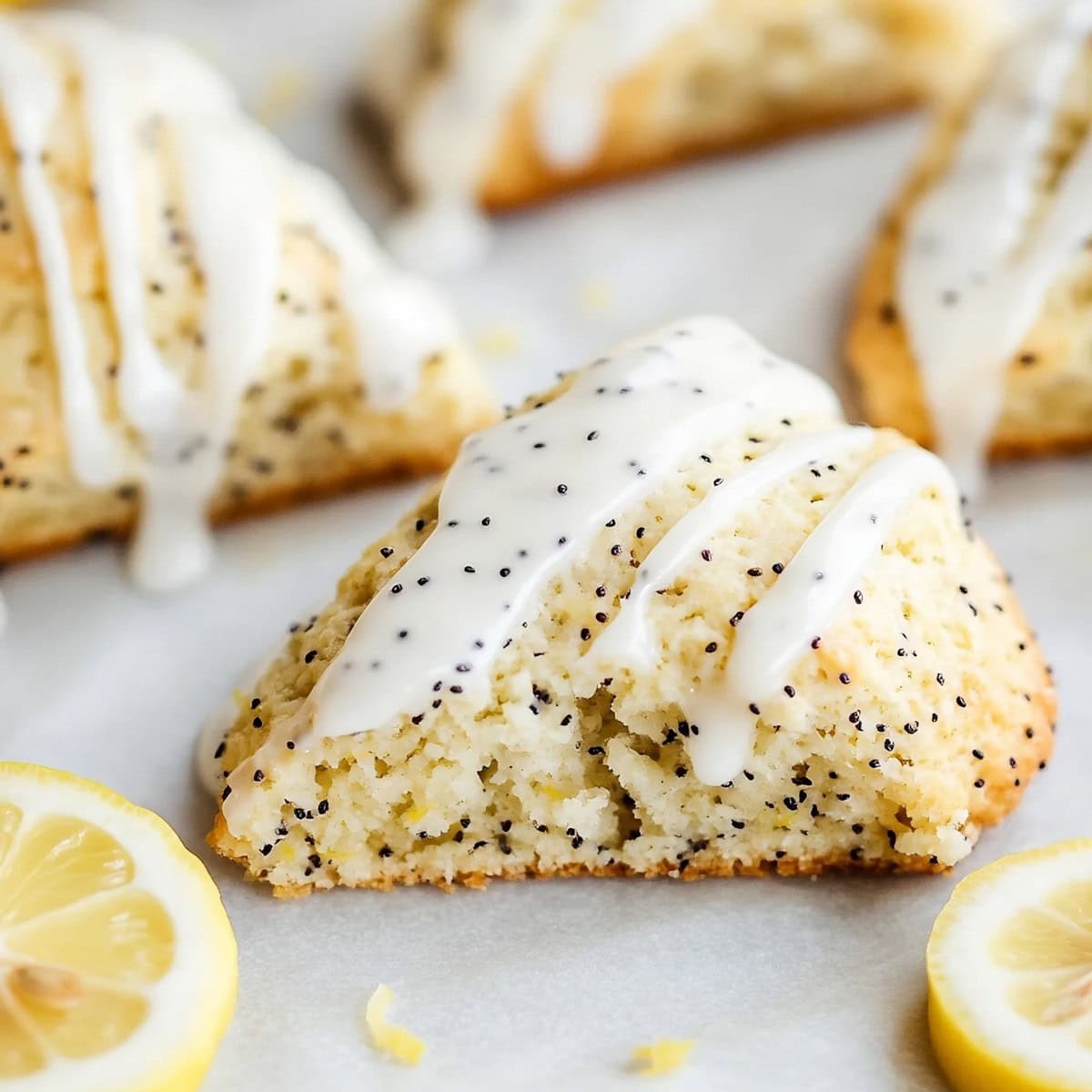 Homemade zesty lemon poppyseed scones on parchment paper with sweet glaze