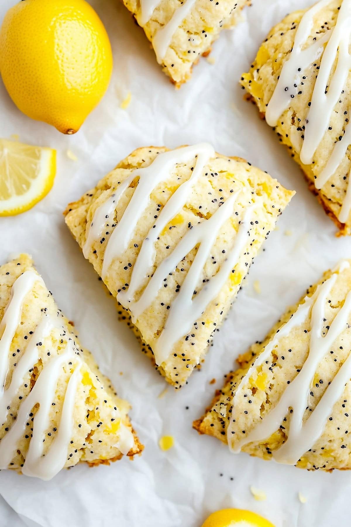 Lemon poppyseed scones with glaze on parchment paper, top down view.