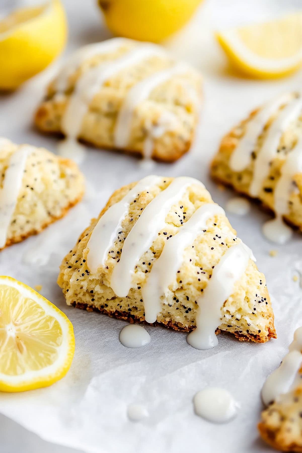 Lemon poppyseed scones with glaze on parchment paper.