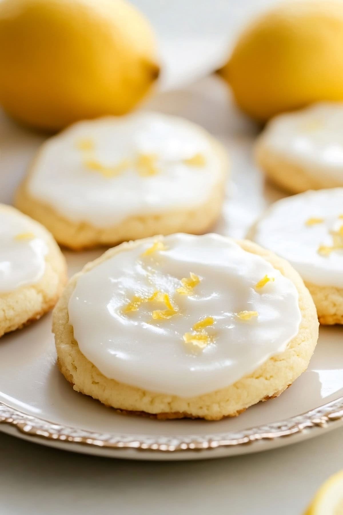 Close-up of lemon sugar cookies with a golden crisp edges and lemon glaze on a plate.