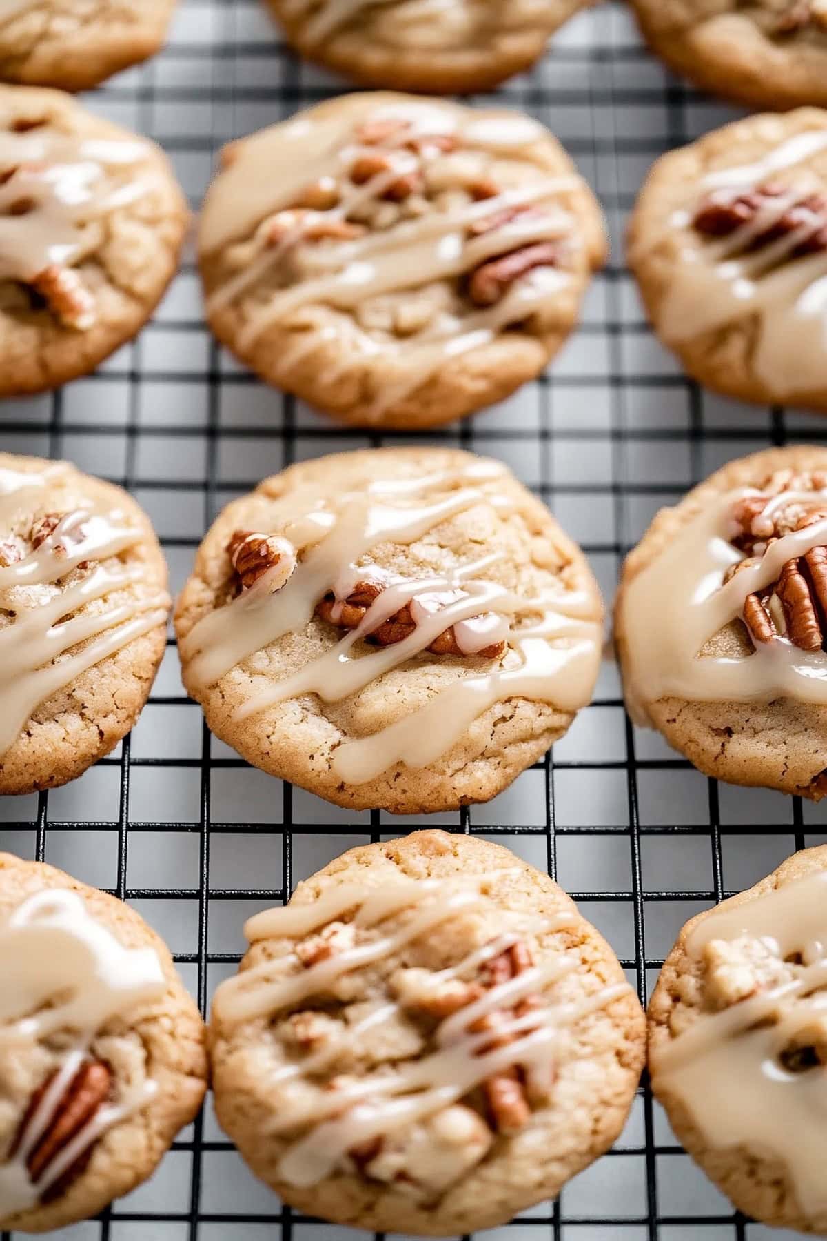 Maple cookies with a thick layer of maple icing arranged neatly on a cooling rack.