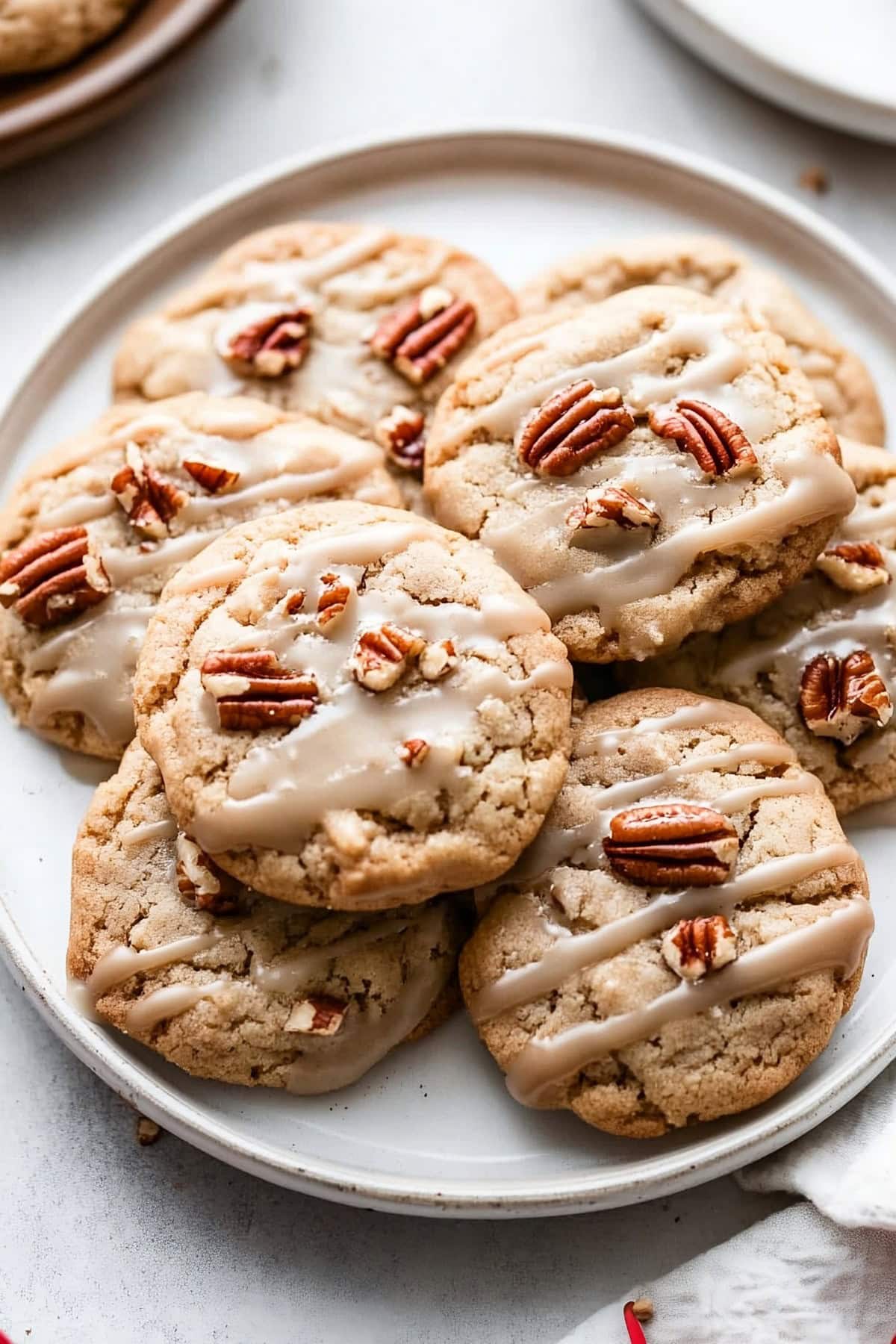 A plate of maple cookies with rich maple icing and chopped pecans, top view