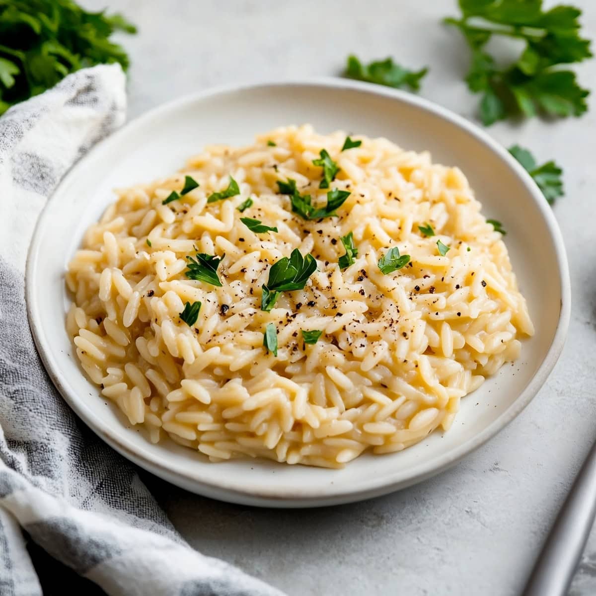 A bowl of orzo risotto with fresh herbs and black pepper on the top.