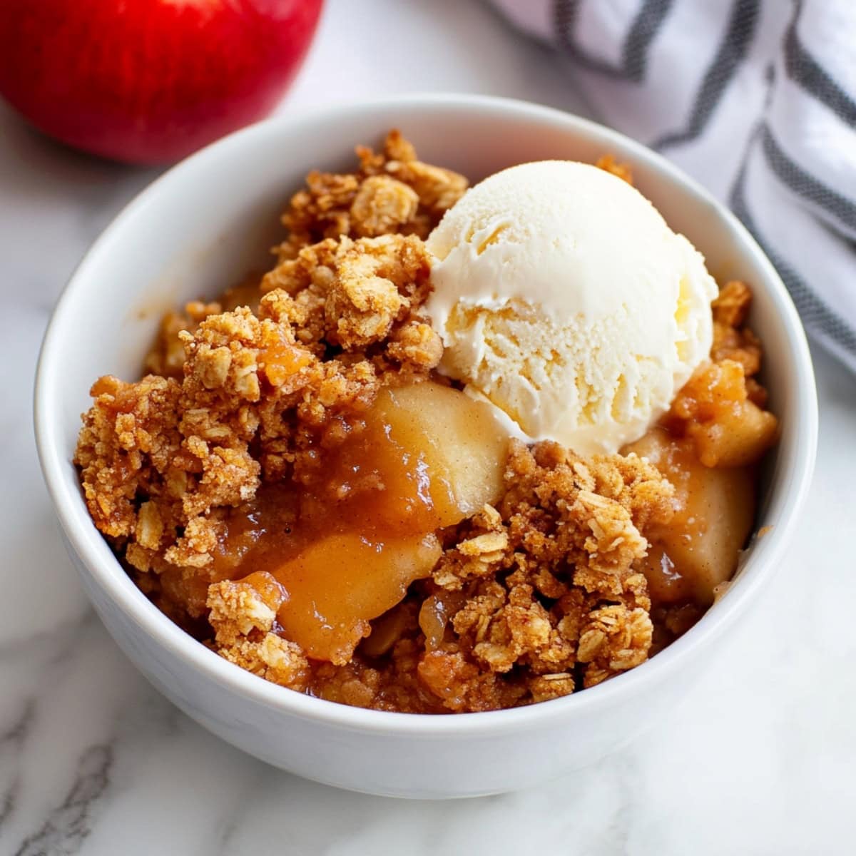 A bowl of apple crisp with a scoop of ice cream.