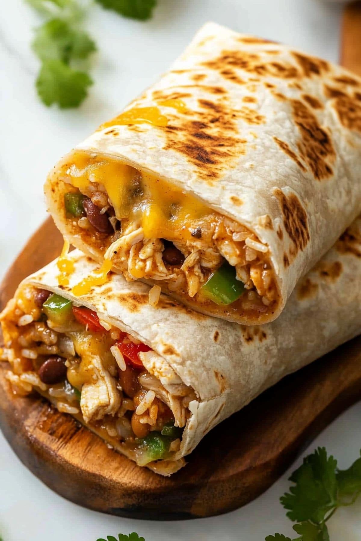 Chicken burritos stacked on top of each other on a wooden board.