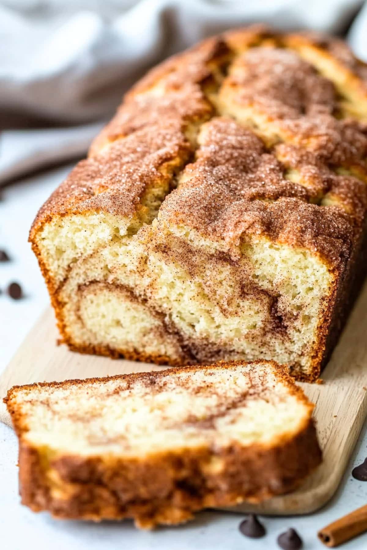 Sliced snickerdoodle loaf bread sitting on a wooden chopping board.