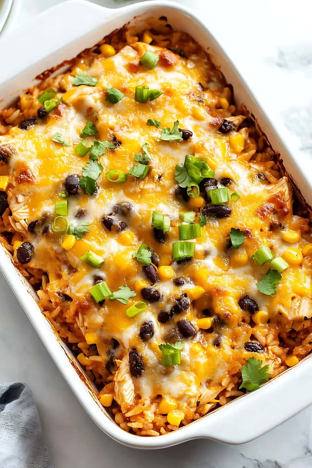 Baked chicken casserole with rice, black beans and corn in a baking dish.