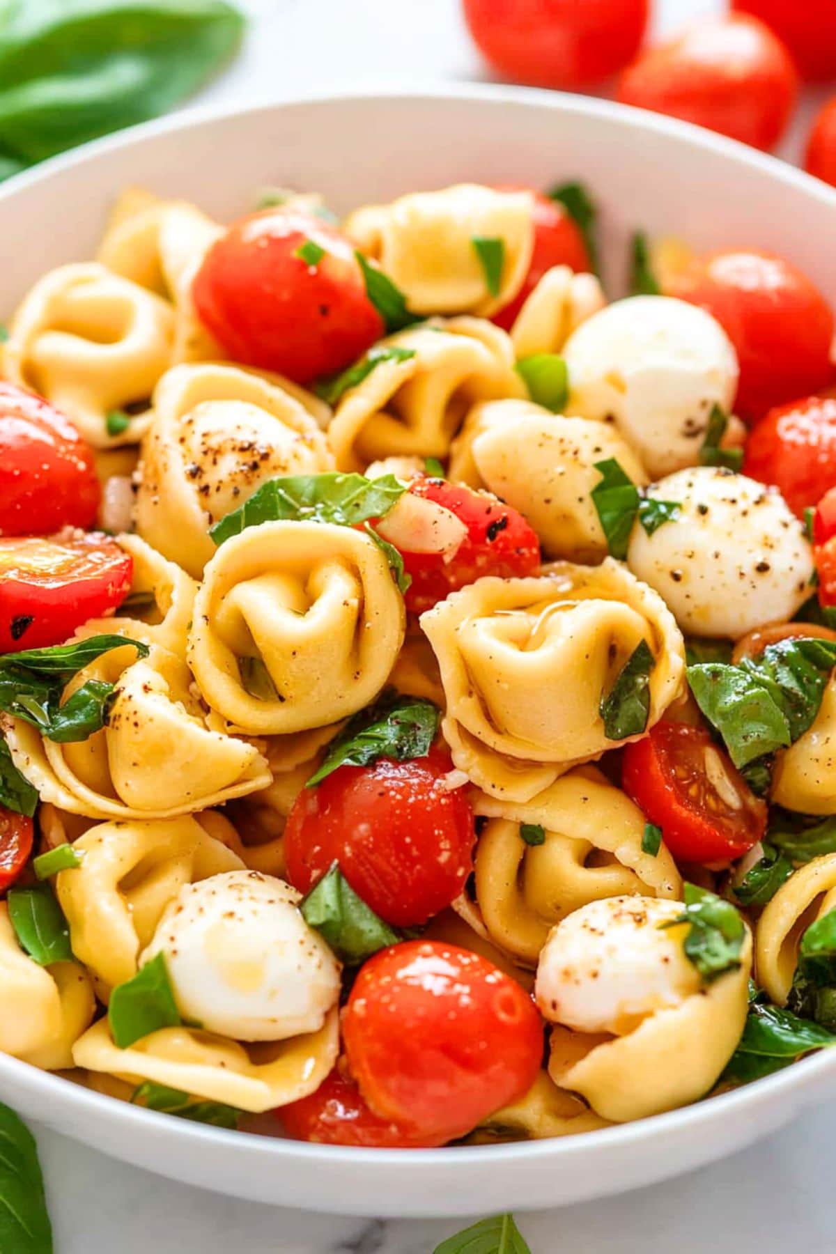 Salad made with cheese tortellini with juicy cherry tomatoes, mozzarella pearls, and fresh basil.