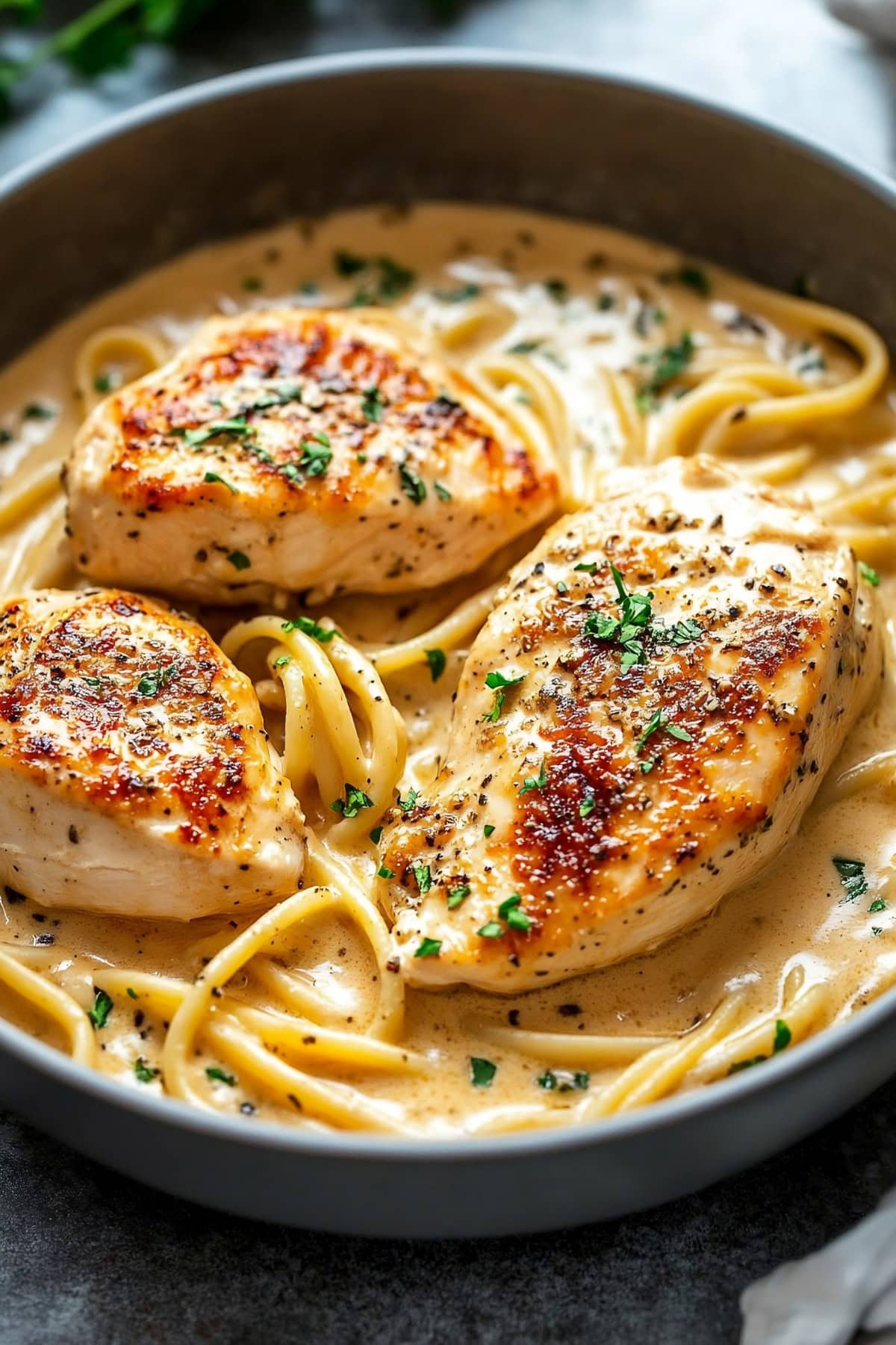 chicken breasts and pasta with creamy sauce in a bowl.