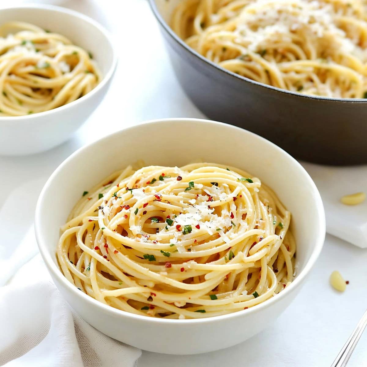 Serving of spaghetti aglio e aolio in a bowl garnished with parmesan cheese.