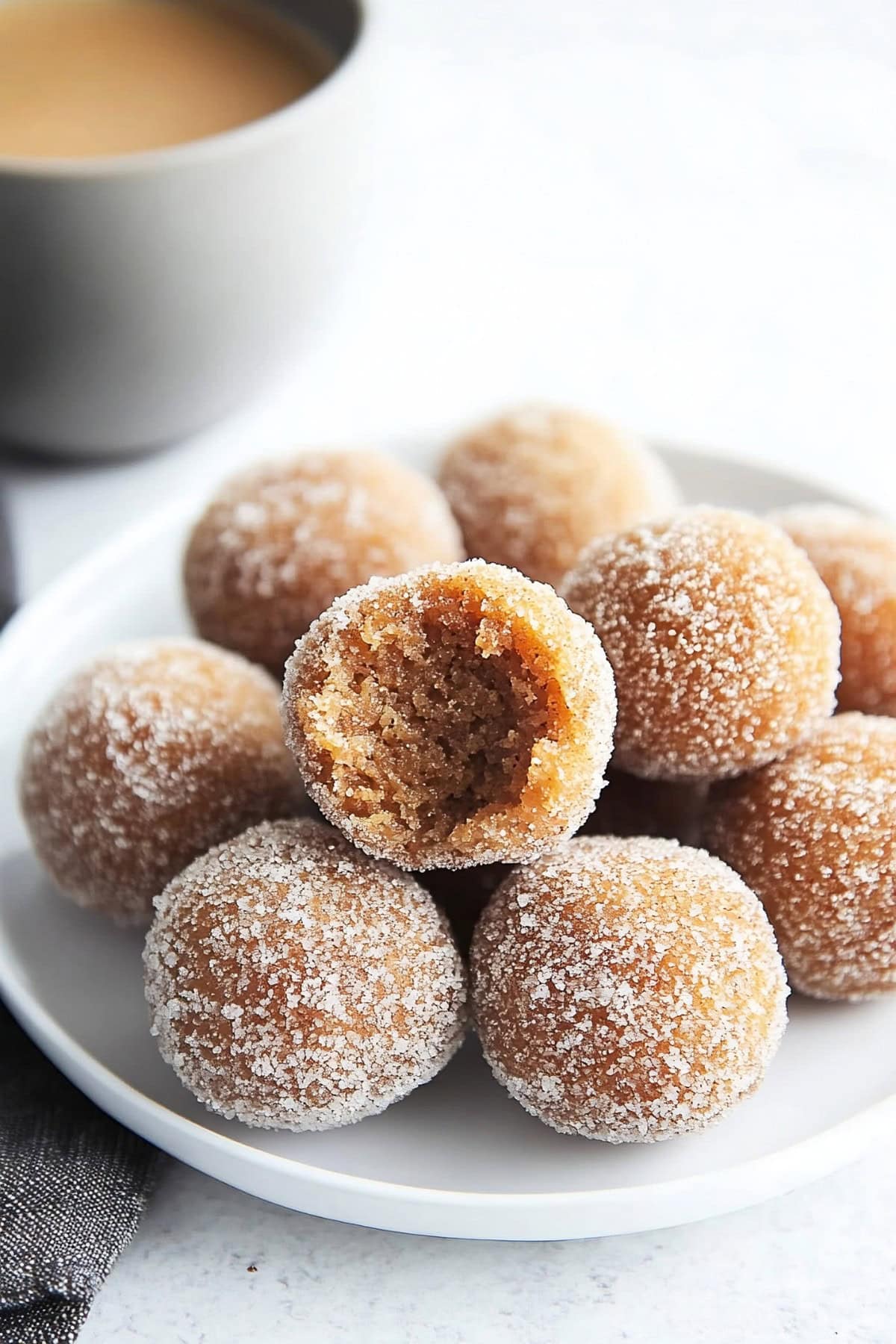 Baked pumpkin spice donut holes with sugar, a cup of coffee on the side.